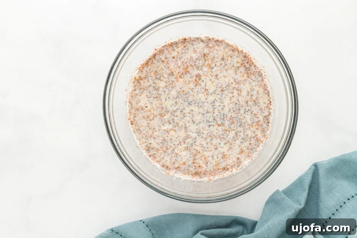 All ingredients for banana chia pudding, including mashed banana, milk, chia seeds, honey, vanilla, and cinnamon, combined in a glass bowl.