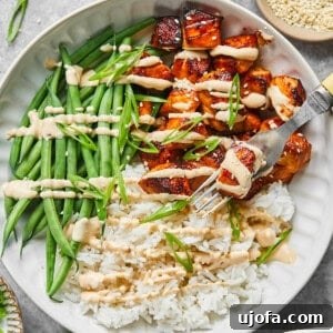 bang bang salmon bites with sauce, rice and green beans in a bowl