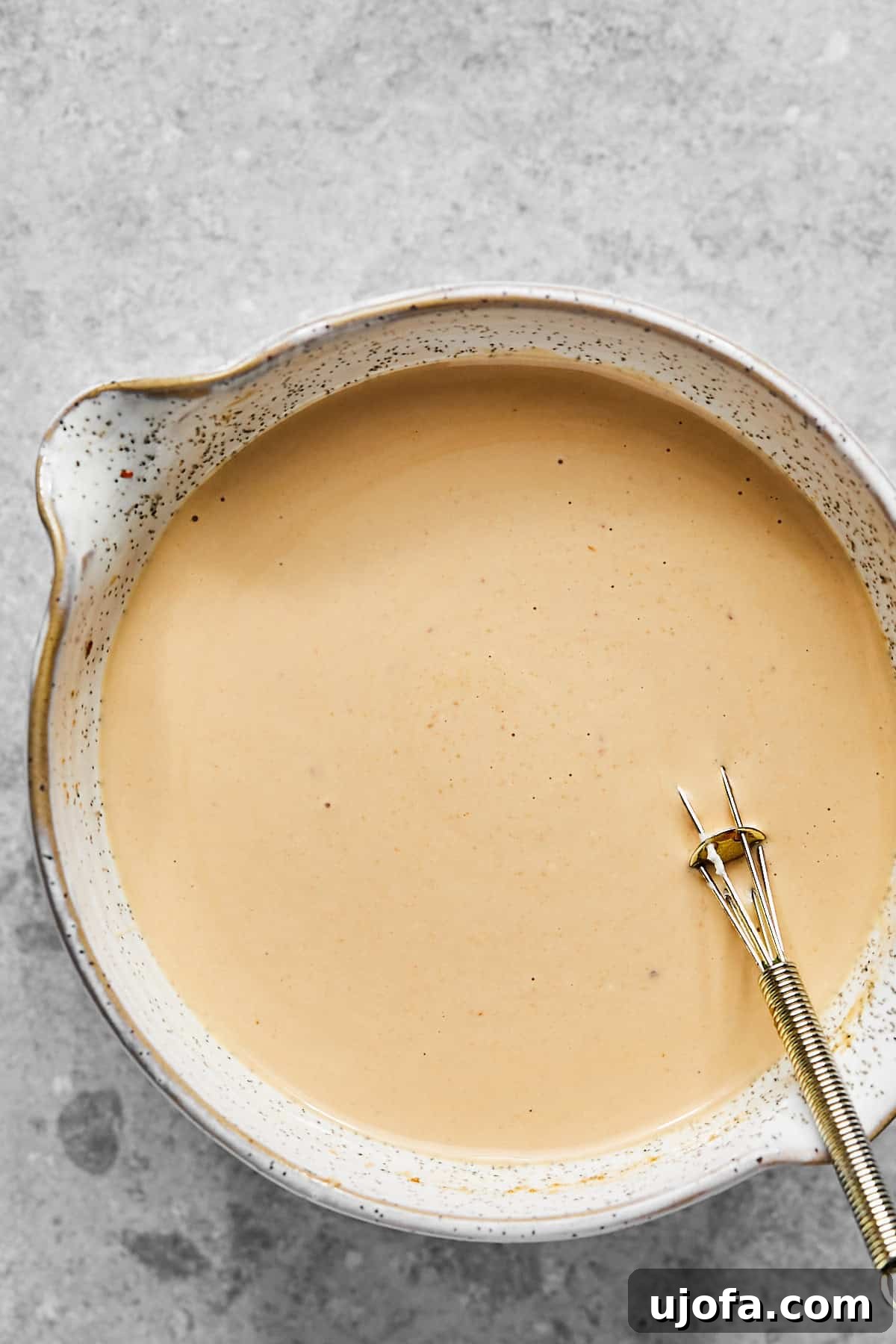 bang bang sauce in a bowl with a small whisk