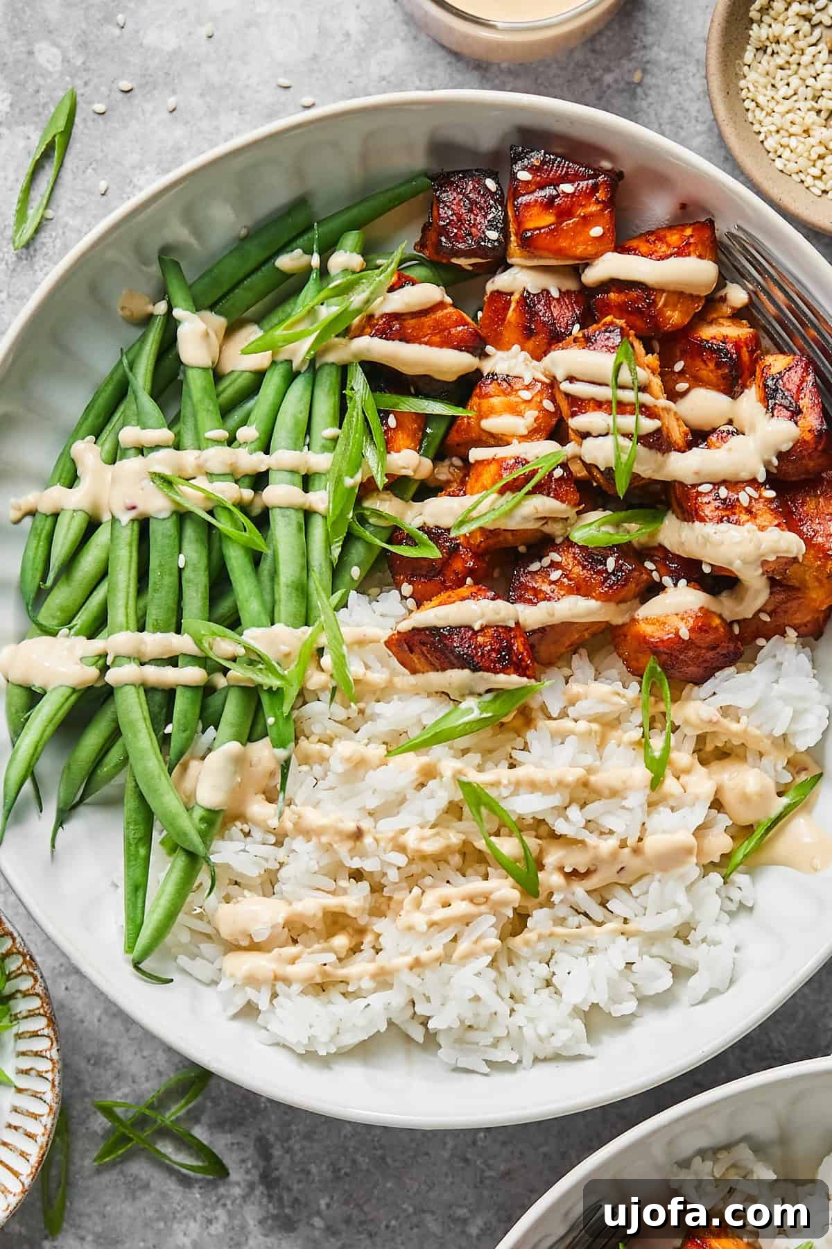green beans, salmon, and rice with sauce in a bowl topped with sesame seeds