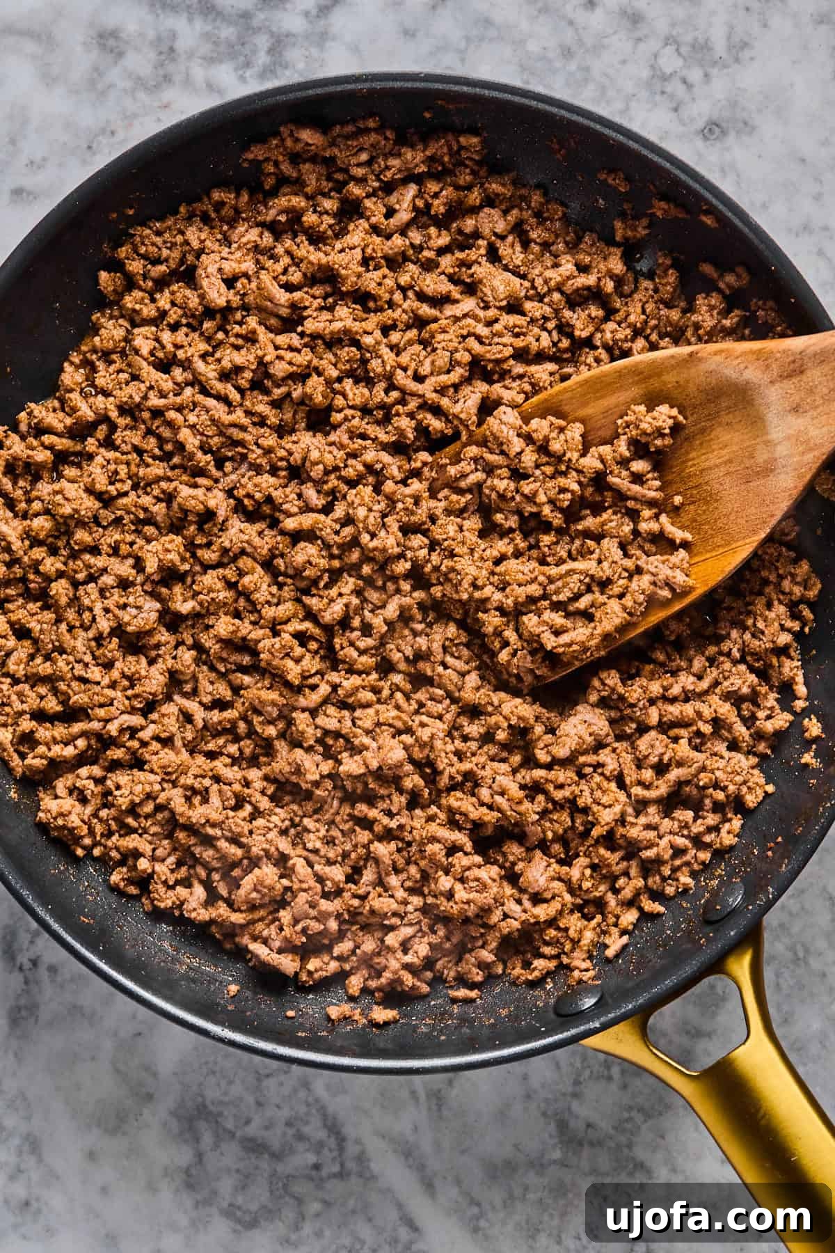 Perfectly browned and crumbled taco meat in a skillet, thoroughly cooked and ready to be added to the taco bowl.