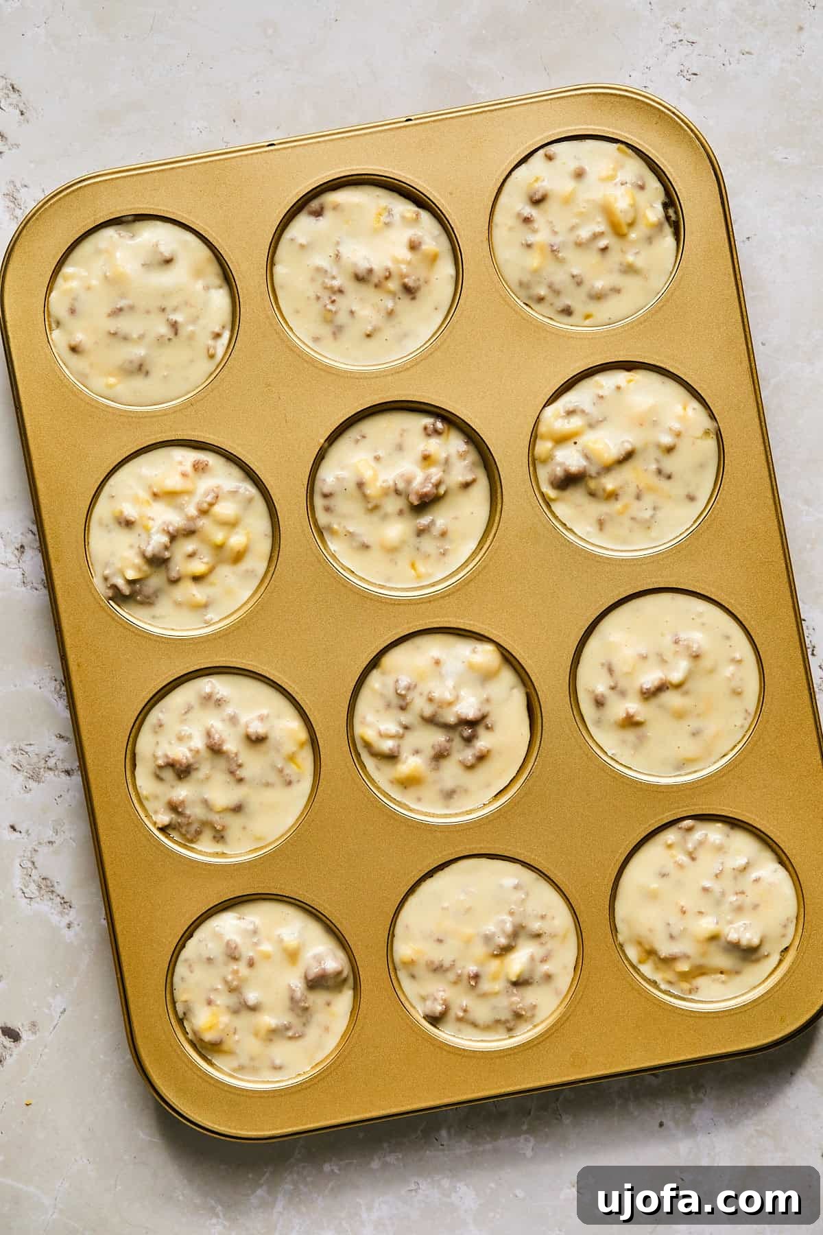 Dividing McGriddle muffin batter evenly into a greased muffin tin
