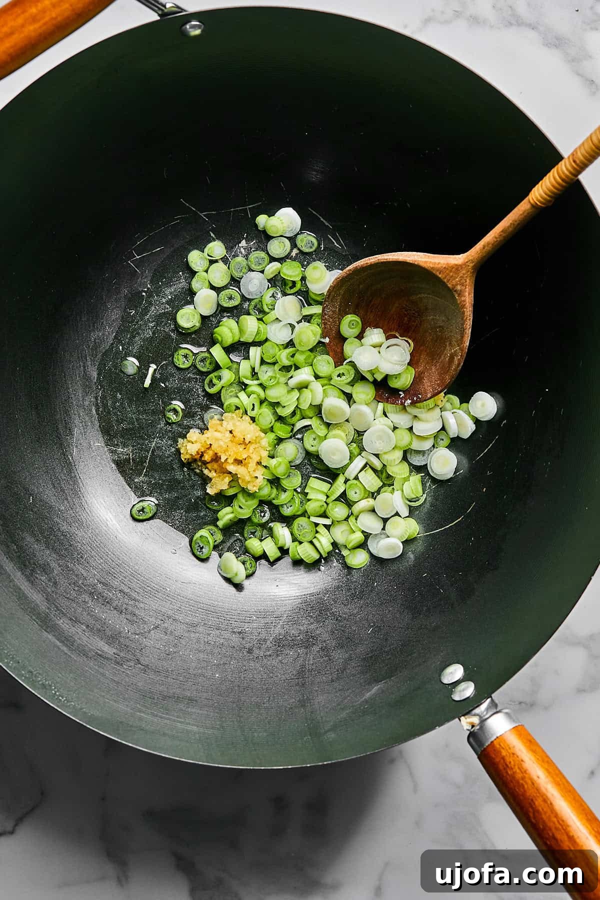 Garlic and green onions sautéing in avocado oil in a skillet
