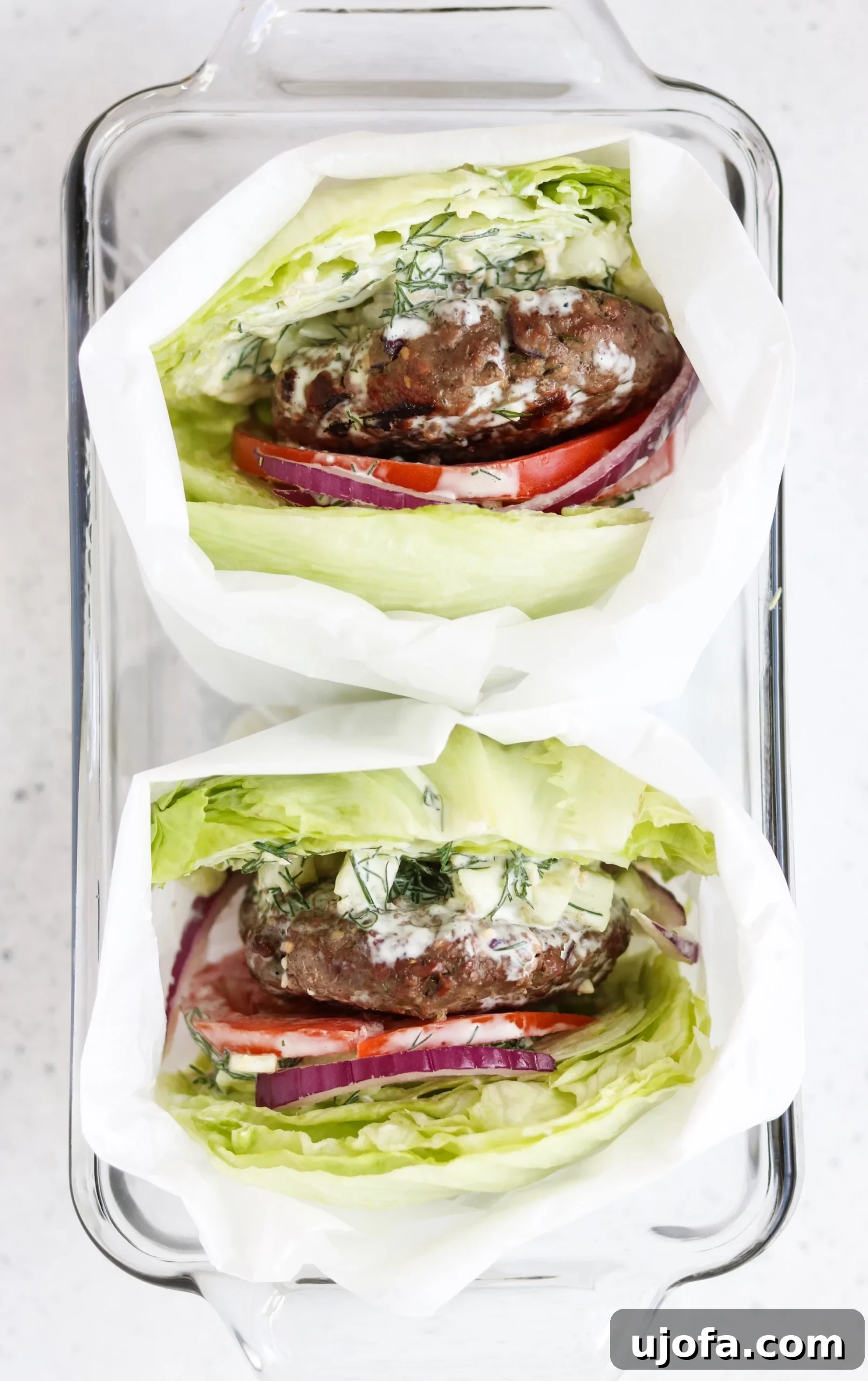 A close-up shot of a single low-carb Greek burger with a thick beef patty, visible red onion, and fresh toppings, ready to be enjoyed.