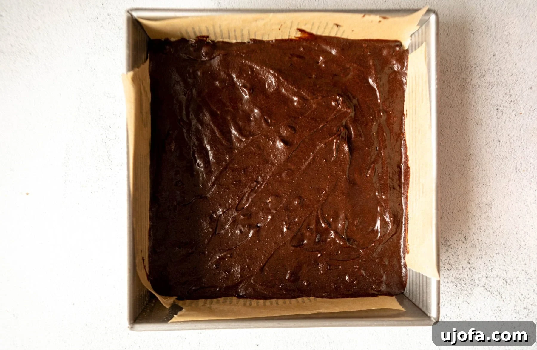 Fudgy Coconut Flour Brownies 10 Brownie batter for coconut flour brownies spread evenly in a parchment-lined baking pan, ready for the oven.