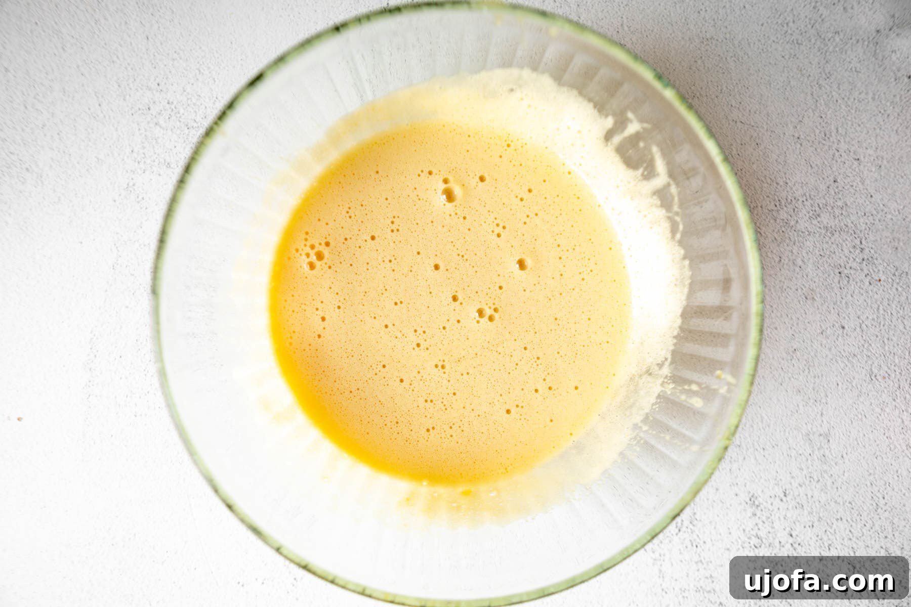 Fudgy Coconut Flour Brownies 8 Wet ingredients for coconut flour brownies in a glass mixing bowl, a creamy yellow mixture.