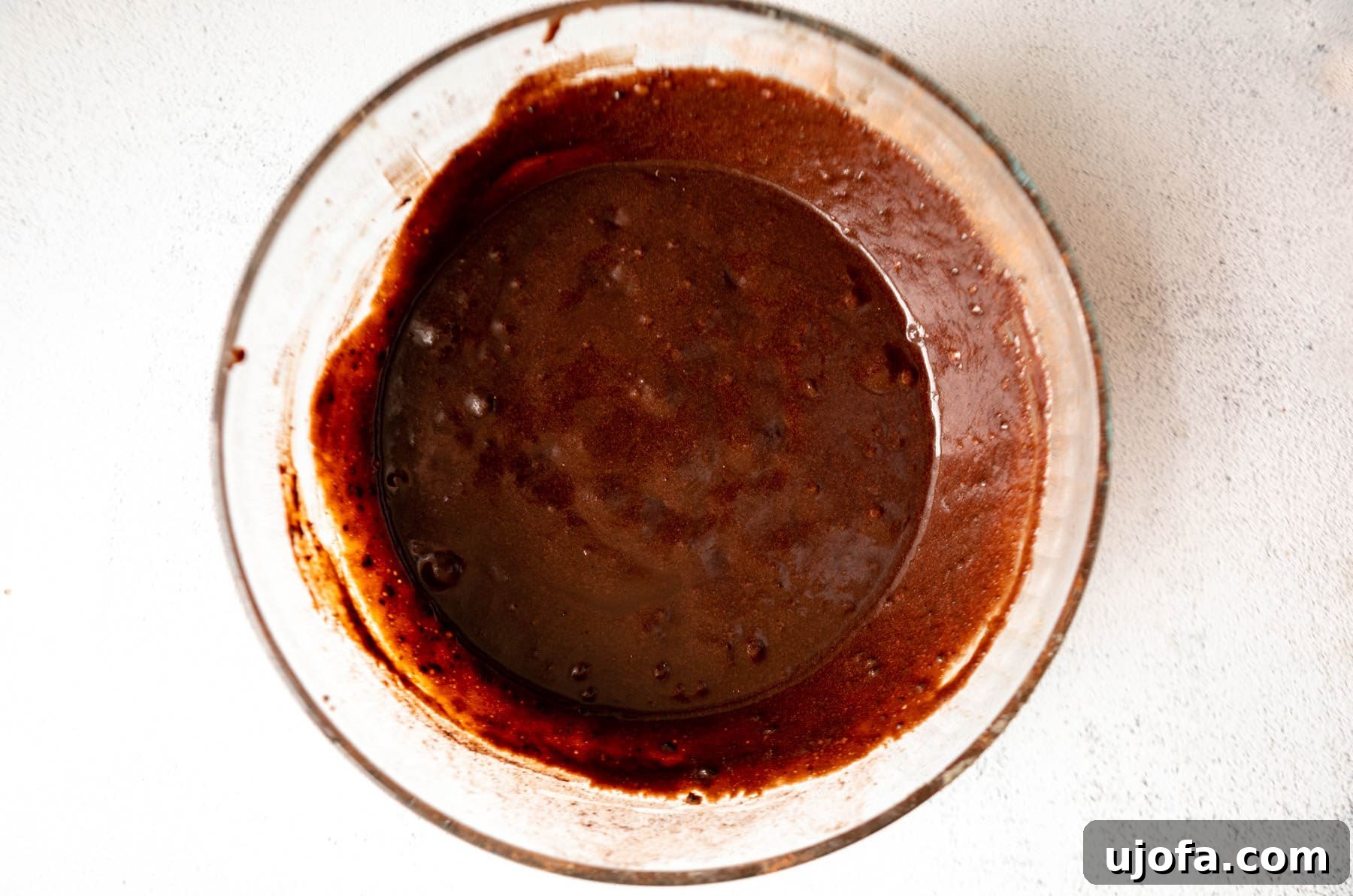 Fudgy Coconut Flour Brownies 9 Brownie batter for coconut flour brownies in a glass mixing bowl, dark brown and thick.