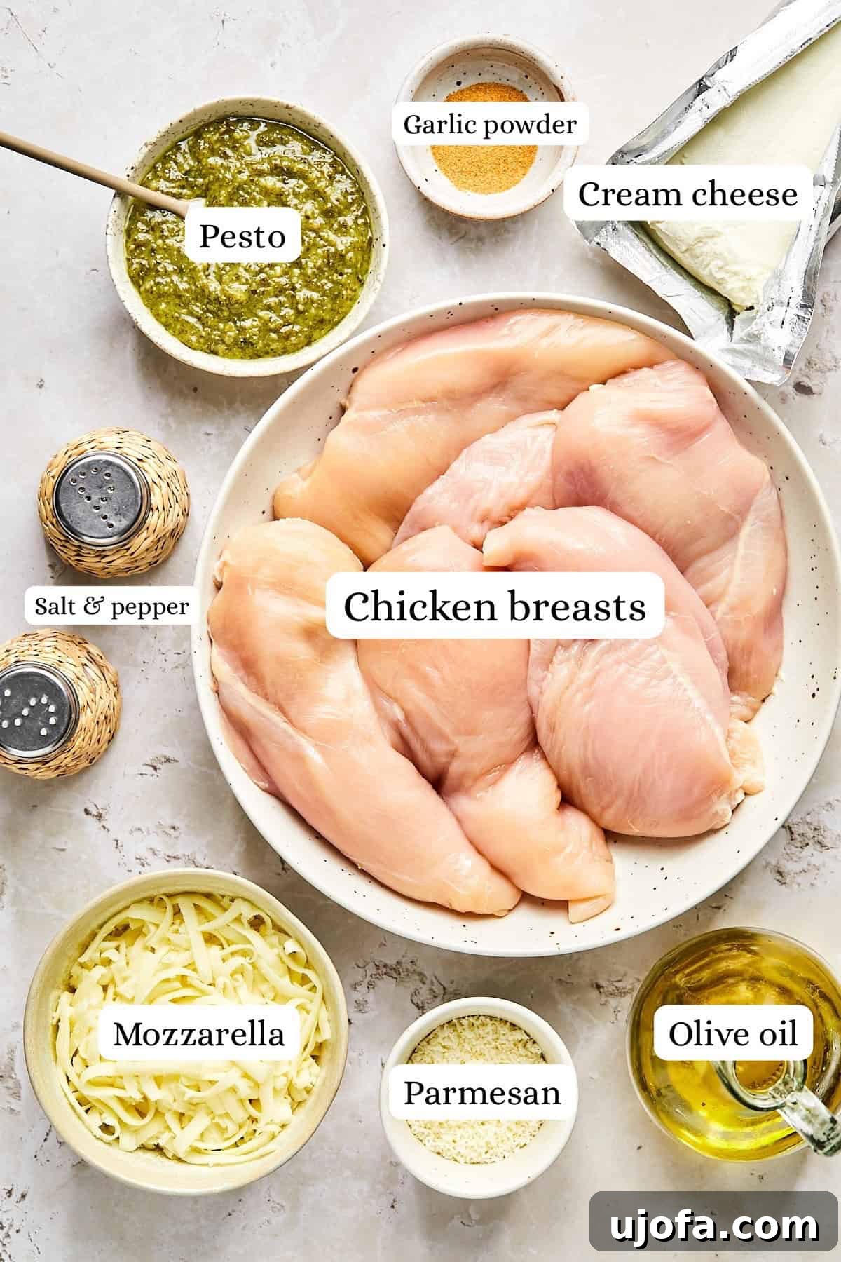 Ingredients for pesto chicken bake including chicken breasts, jarred pesto, cream cheese, parmesan, mozzarella, and seasonings