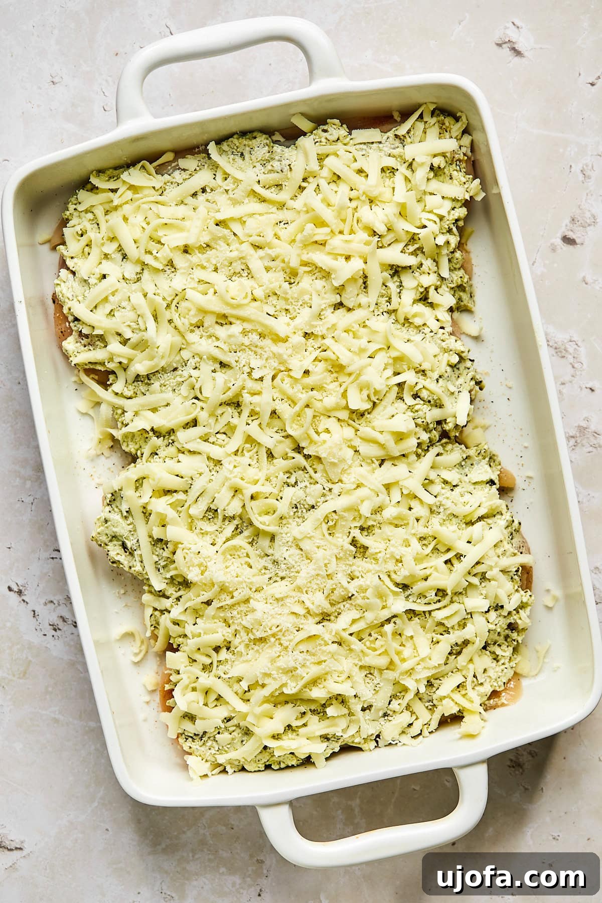 Chicken covered generously with parmesan and mozzarella cheese before baking
