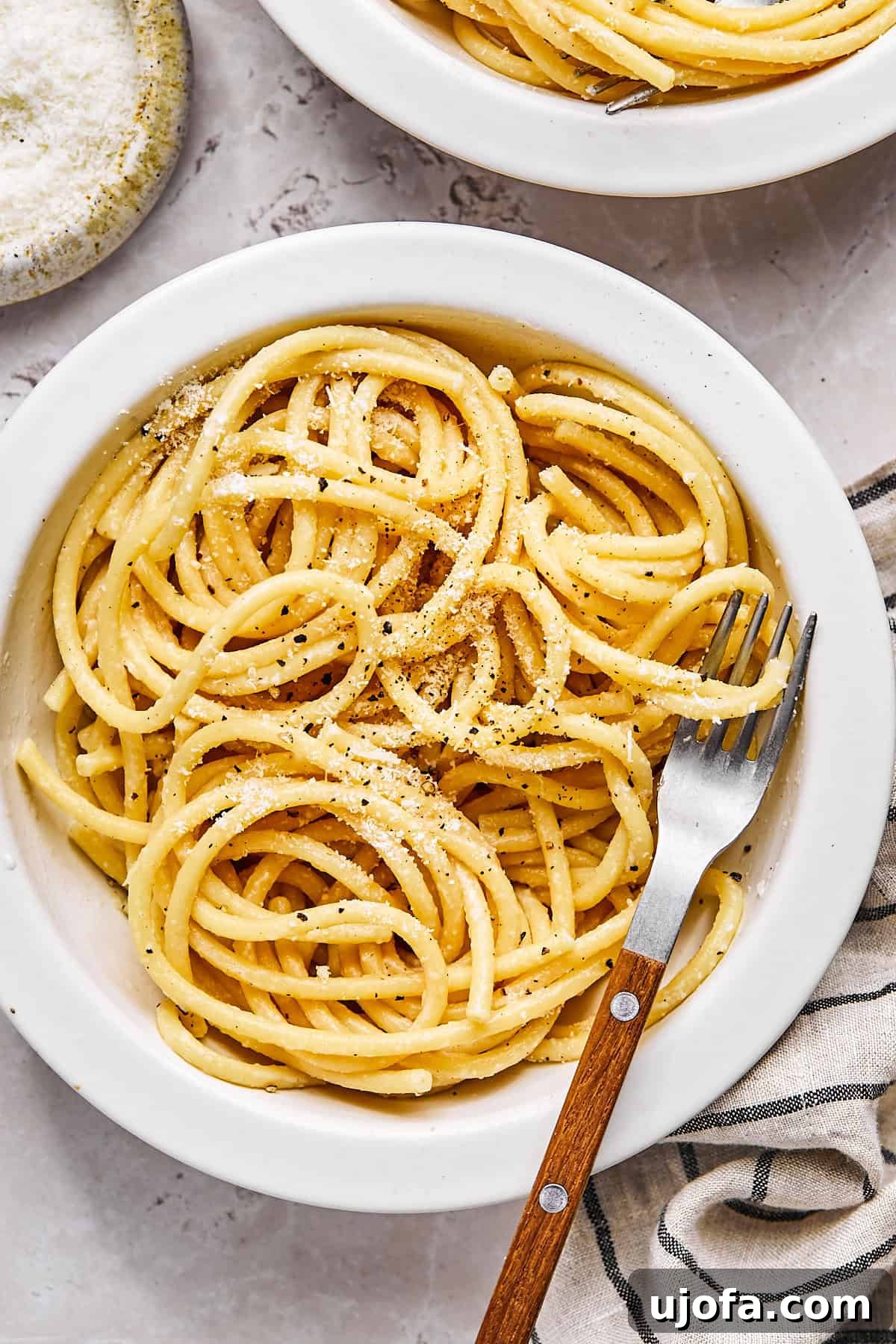 Simple 5 Ingredient Gluten Free Bucatini Cacio e Pepe 2 Gluten-free bucatini cacio e pepe served in a white bowl with cracked black pepper and pecorino cheese on top