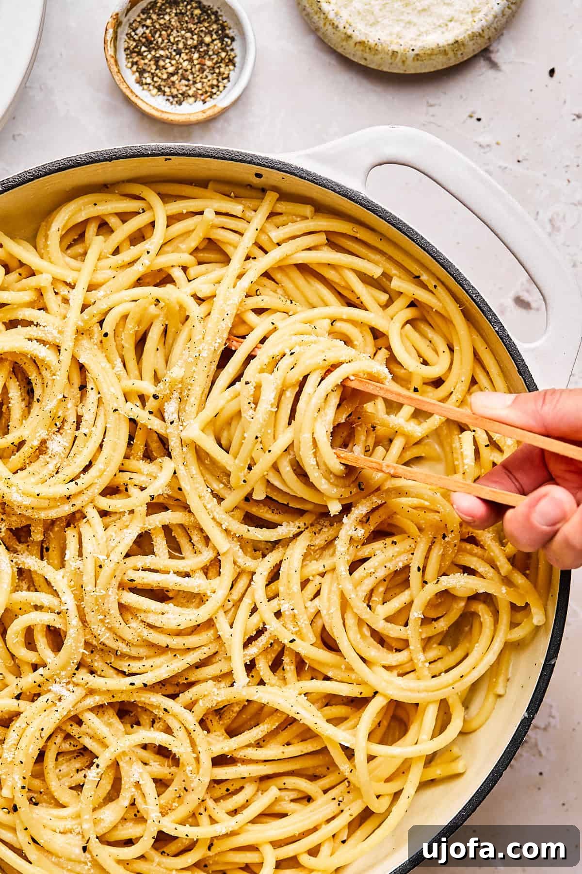 Simple 5 Ingredient Gluten Free Bucatini Cacio e Pepe 8 Close-up of bucatini cacio e pepe twirled on tongs with cracked pepper and grated cheese