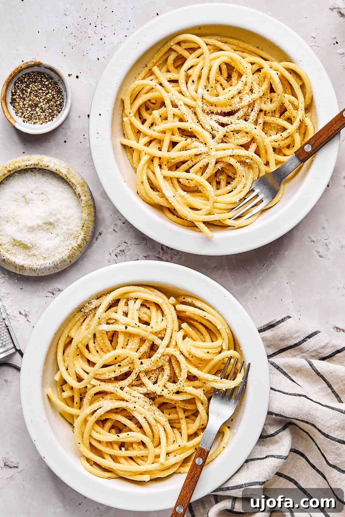 Simple 5 Ingredient Gluten Free Bucatini Cacio e Pepe 9 two bowls of gluten-free bucatini cacio e pepe next to a small dish of cheese and cracked pepper