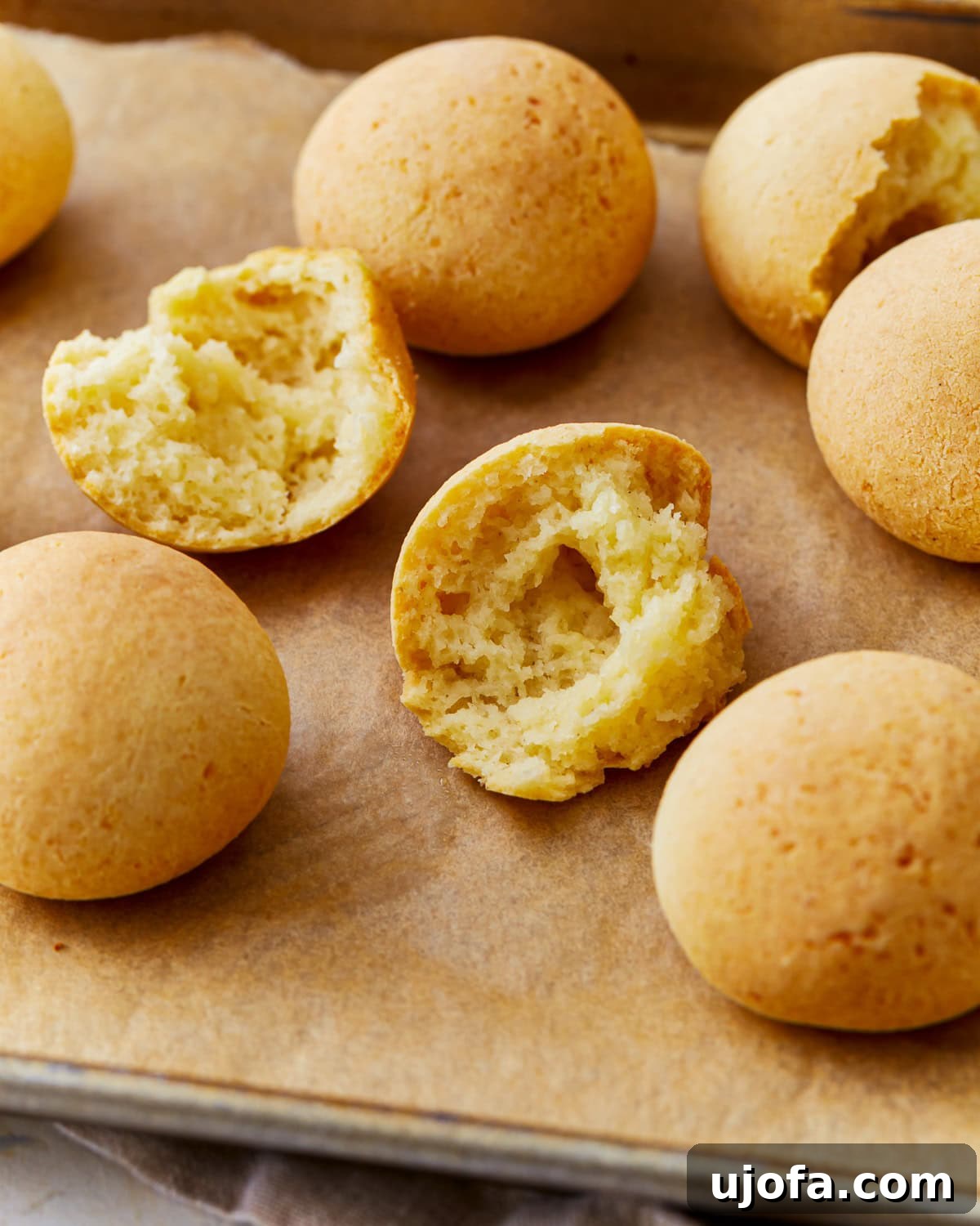 Golden Pandebono Colombian Bakery Classic 2 Freshly baked Pandebono Colombian cheese bread on a parchment lined baking sheet, golden brown and crispy, ready to be enjoyed.