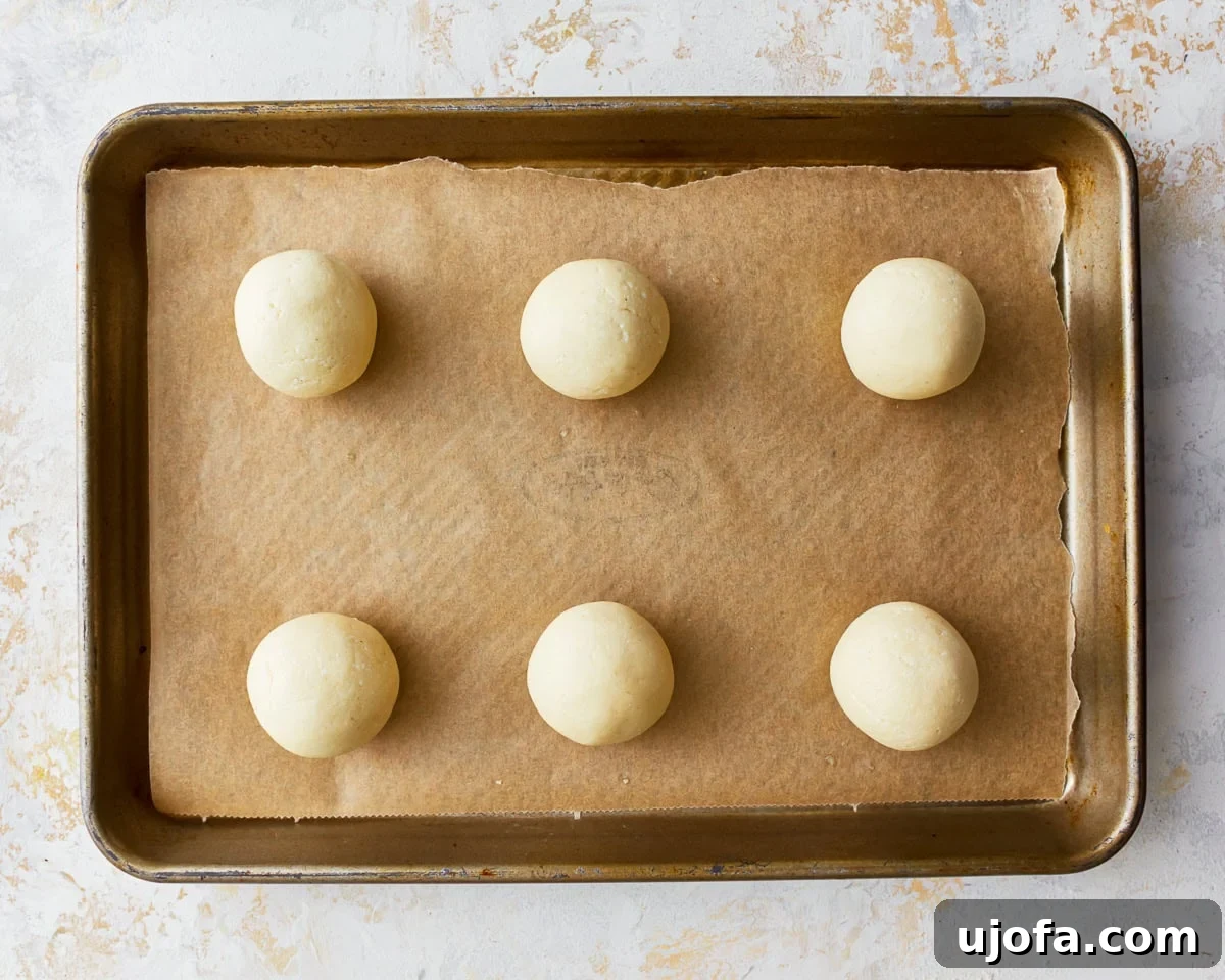 Golden Pandebono Colombian Bakery Classic 10 Shaped pandebono dough balls neatly arranged on a parchment lined baking sheet, spaced out for optimal baking.