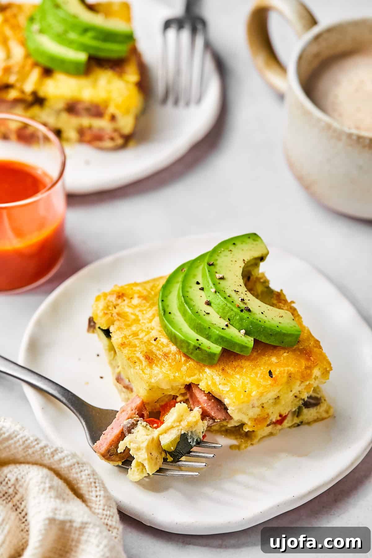 Hearty Cottage Cheese and Chicken Sausage Brunch Bake 11 Sliced squares of egg bake on a serving plate topped with avocado