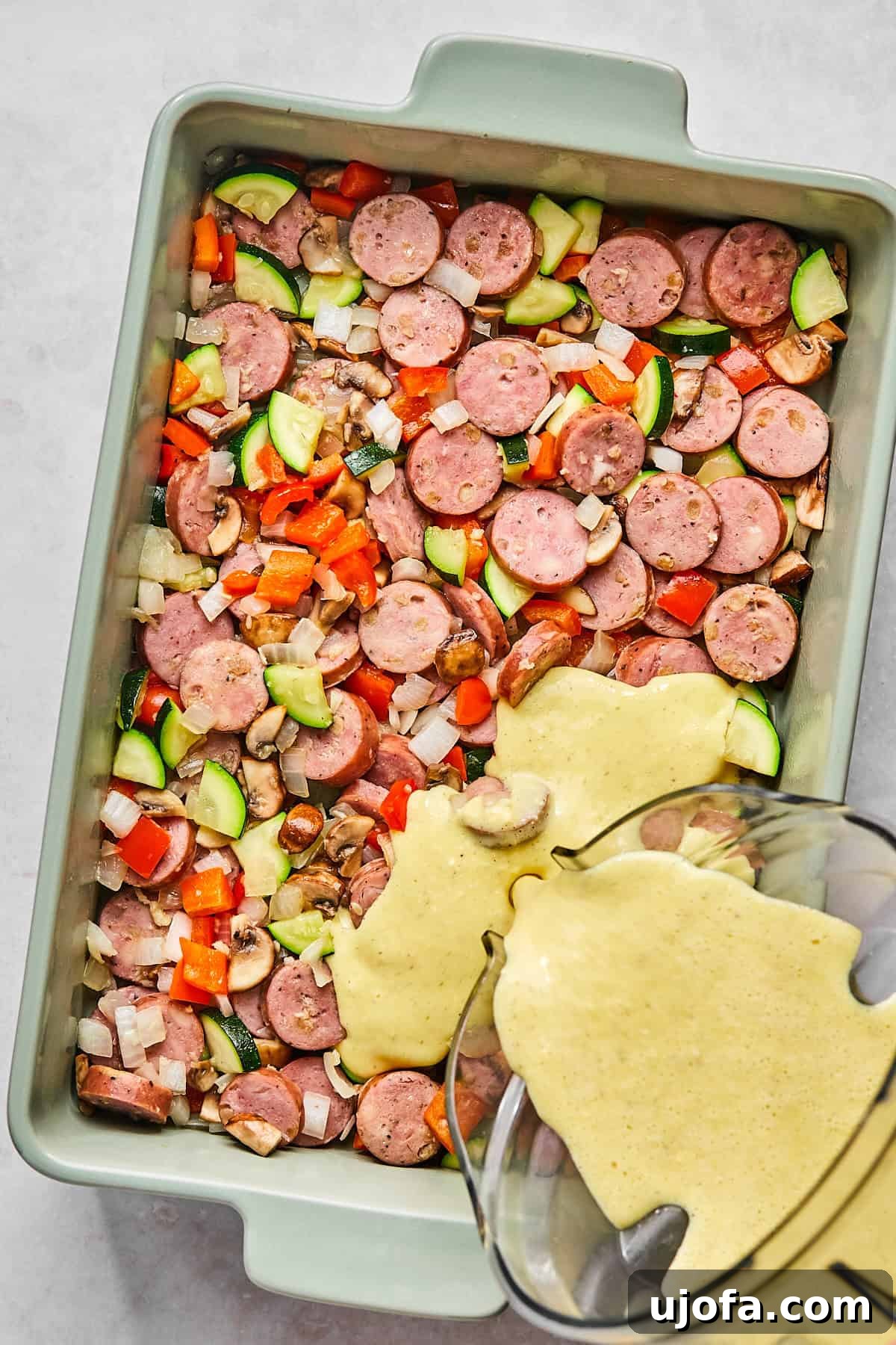 Hearty Cottage Cheese and Chicken Sausage Brunch Bake 7 Casserole dish filled with sautéed veggies and sausage as blended egg mixture is poured on top