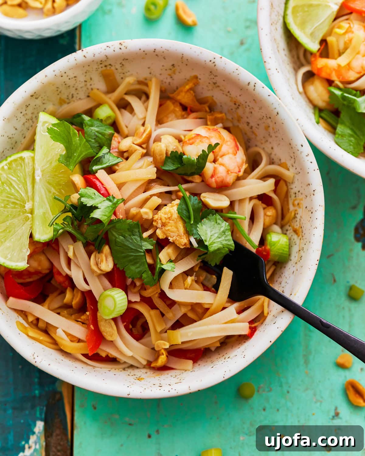 Gluten-free pad thai in a bowl with a fork, ready to be enjoyed.