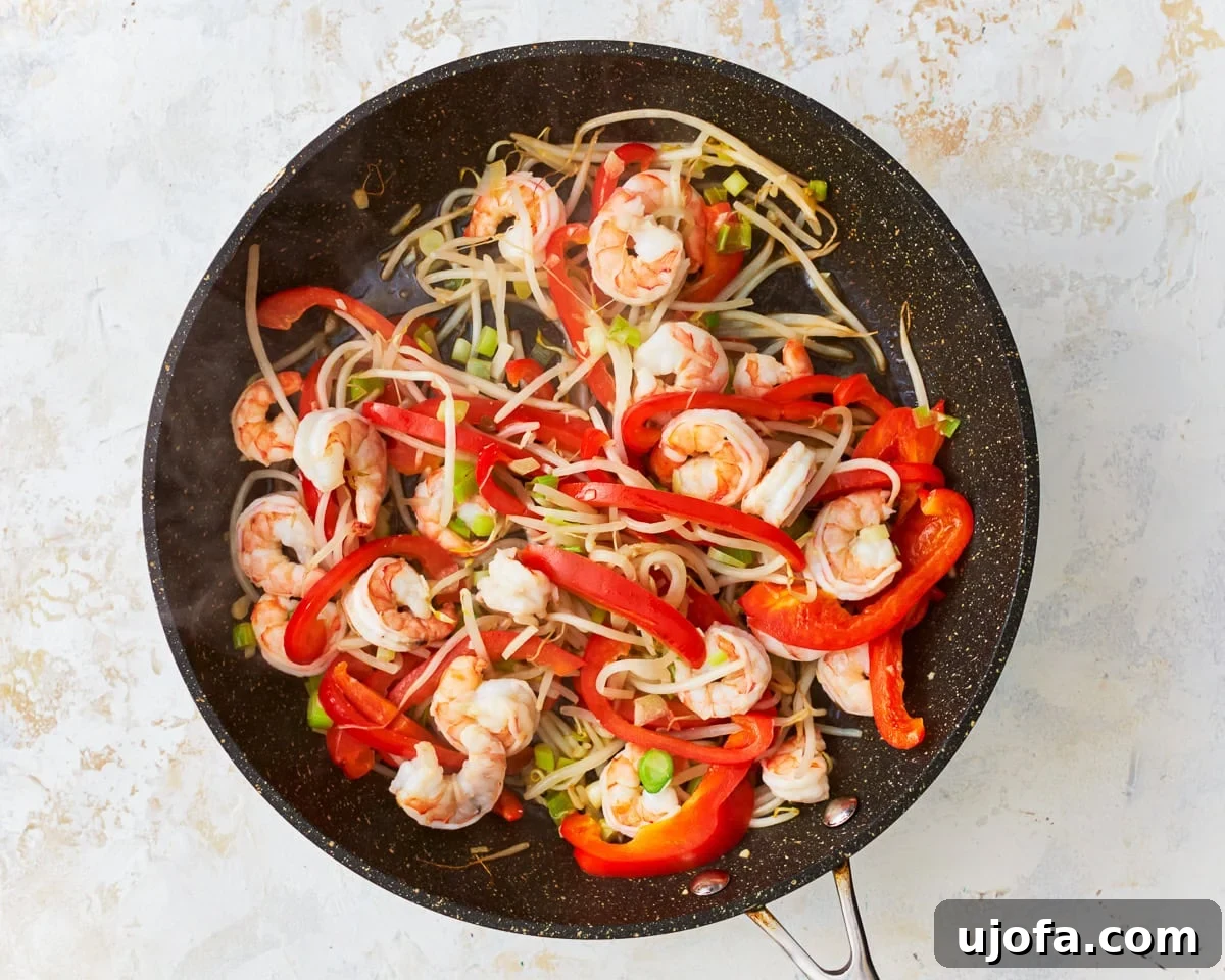 Shrimp and vegetables cooking together in a skillet for Pad Thai.