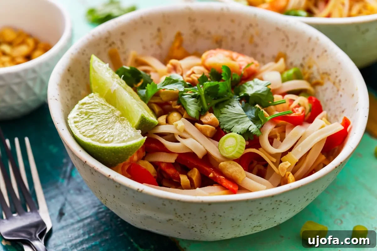Gluten-free pad thai artfully arranged with cilantro, green onions, and lime wedges on top.