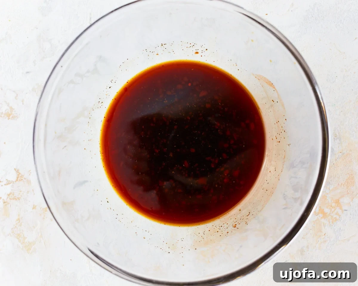 Pad Thai sauce ingredients being whisked together in a glass mixing bowl.