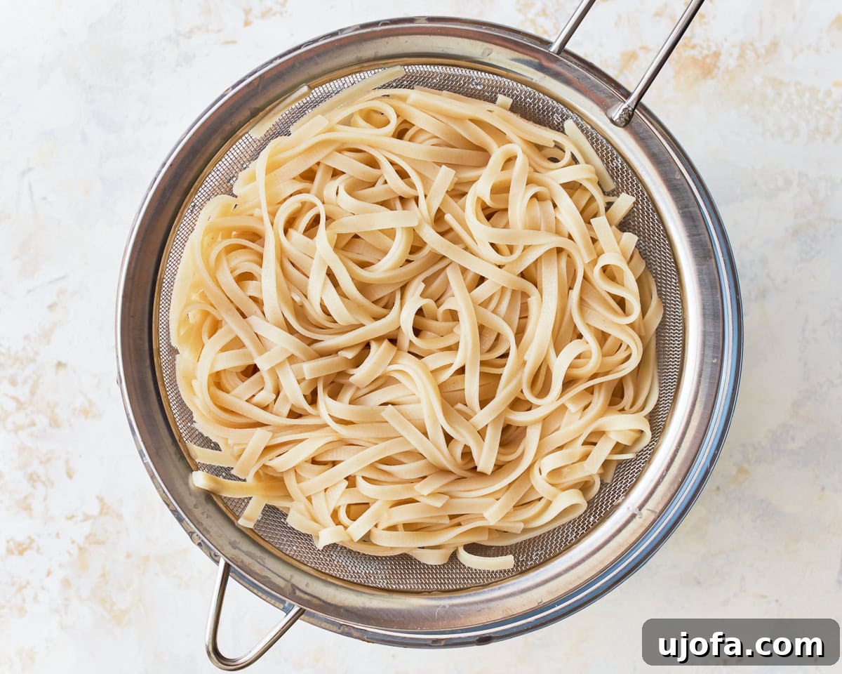 Cooked rice noodles, perfectly al dente, resting in a colander after rinsing.