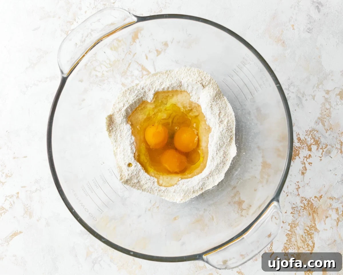 Eggs added to the dry ingredients for almond flour pasta in a bowl