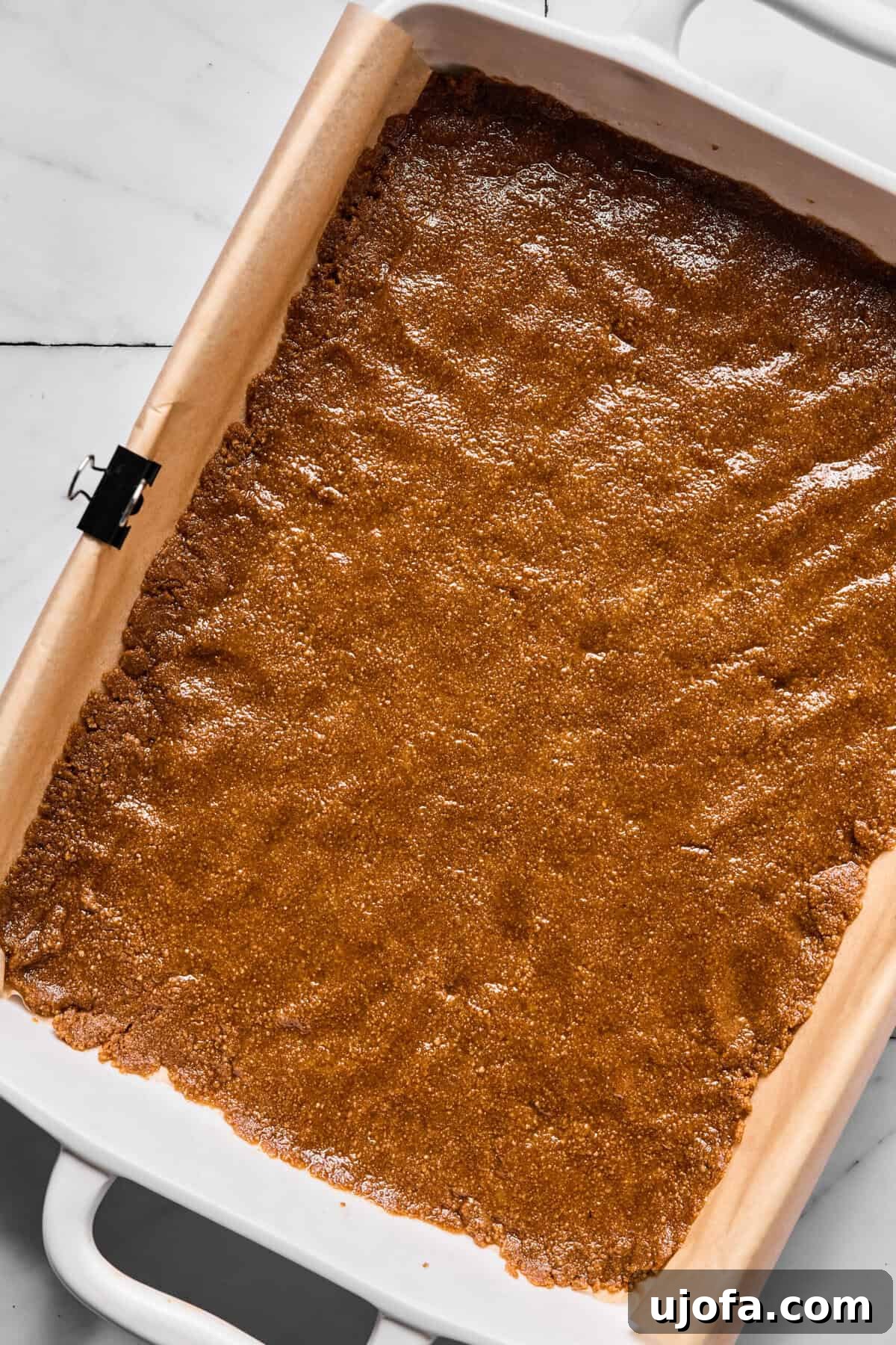 Wondrously Easy Allergen Friendly Bars 5 Pressed Sweet Thins crust evenly packed into parchment-lined baking dish, forming a solid base.