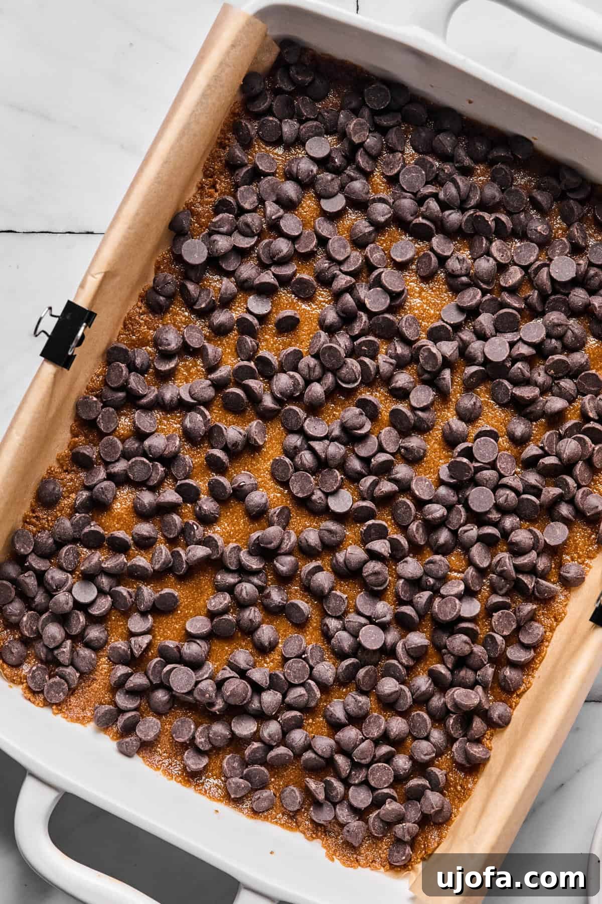 Wondrously Easy Allergen Friendly Bars 6 Dark chocolate chips layered over gluten-free crust in baking pan, ready for more toppings.