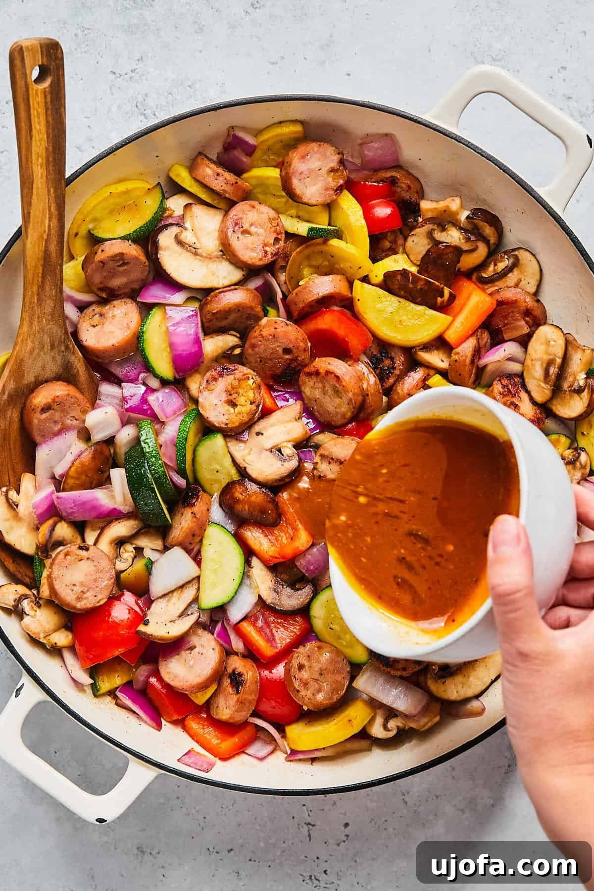 Apple Sausage Chicken Skillet Sensation 9 Pouring sauce into skillet with sausage and vegetables