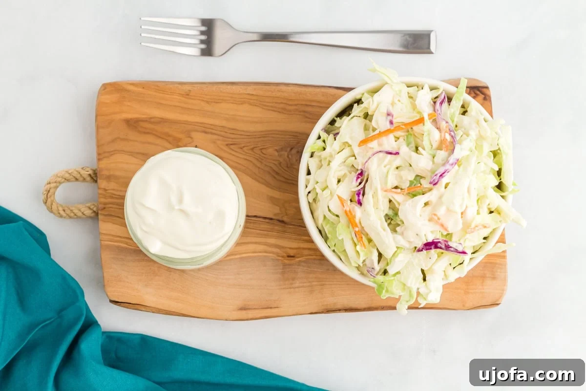Velvet Vegan Mayo 4 A small pot of vegan mayonnaise next to a bowl of coleslaw on a wooden chopping board