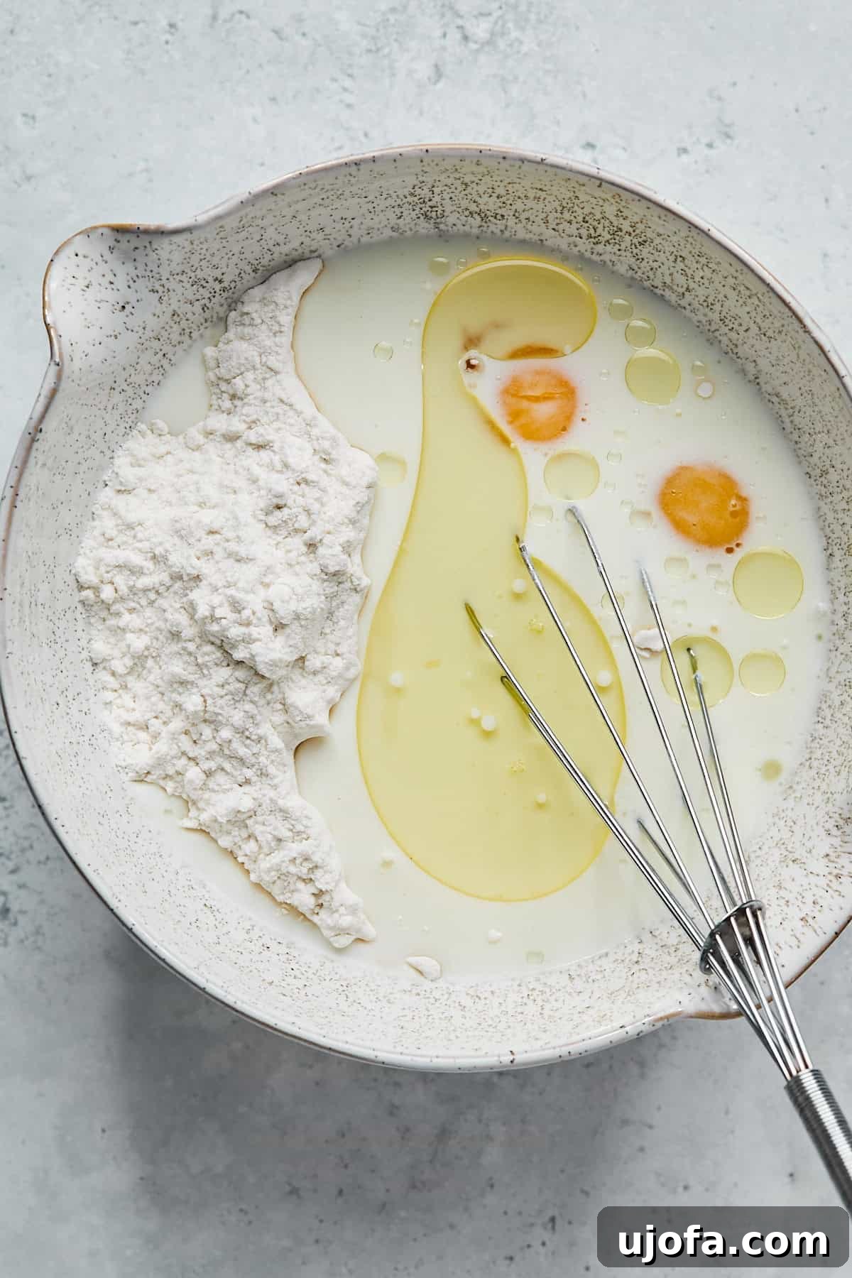 Whisking gluten-free pancake mix, almond milk, eggs, and avocado oil in a bowl