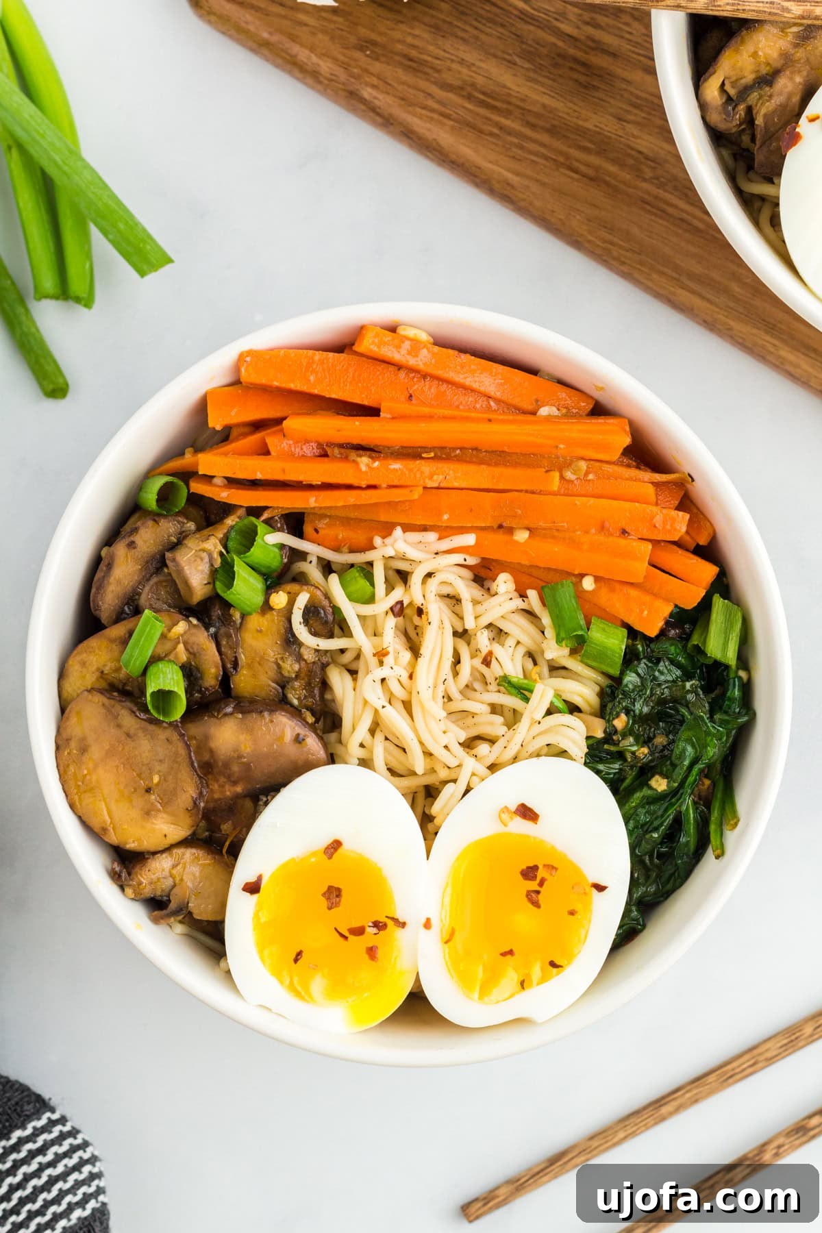 Overhead view of a bowl of gluten-free ramen, garnished with vegetables and a soft-boiled egg.