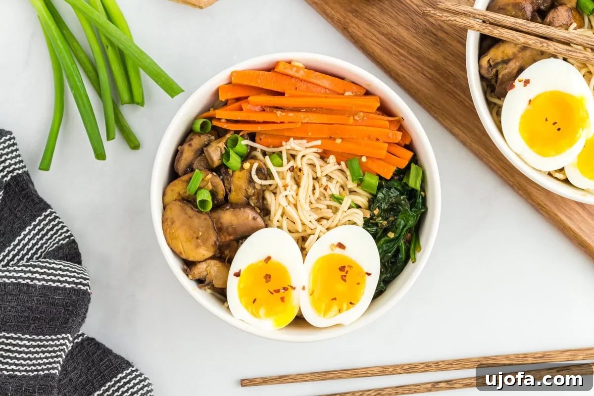A finished bowl of gluten-free ramen, generously topped with soft-boiled eggs, green onions, and fresh vegetables.
