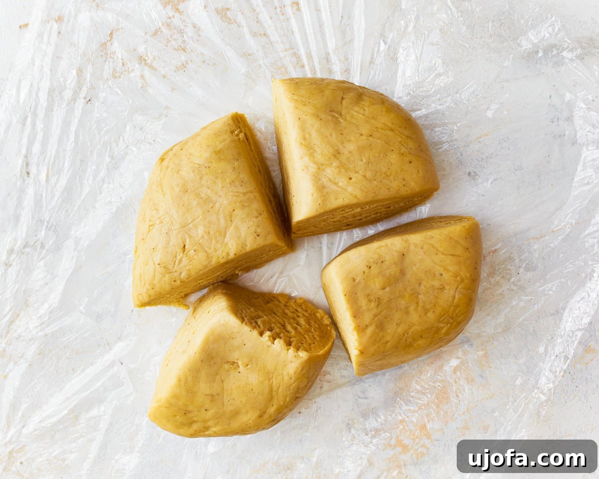 A ball of rested gluten-free egg noodle dough divided into four equal portions, ready for rolling.