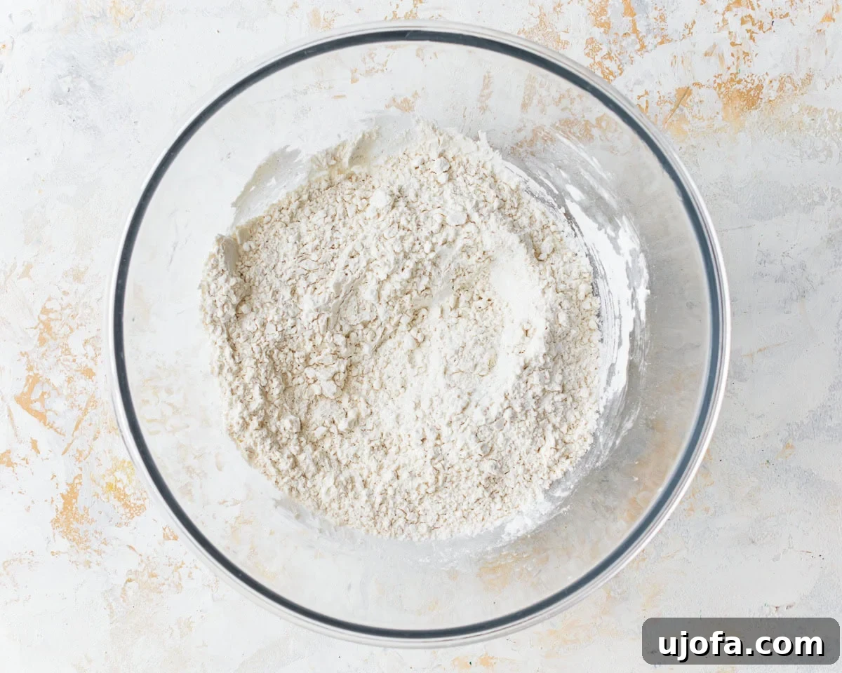 Dry ingredients for gluten-free egg noodles, including all-purpose gluten-free flour, xanthan gum, tapioca starch, and fine sea salt, mixed in a clear glass bowl.