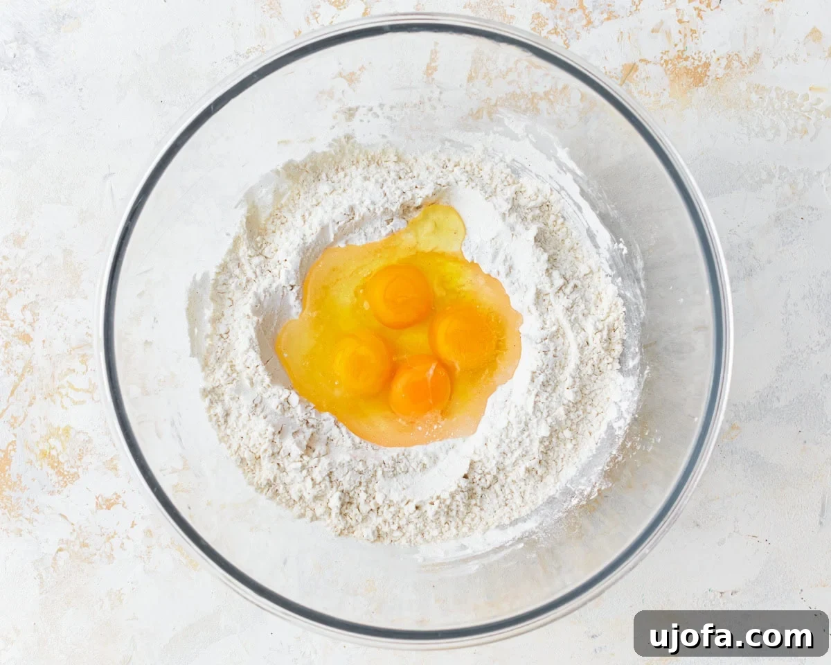 Three large eggs, an extra egg yolk, and a tablespoon of water poured into a well created in the center of the dry gluten-free noodle ingredients.