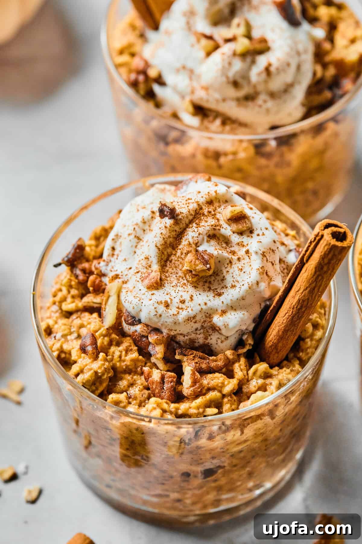 protein pumpkin overnight oats in a glass cup with a cinnamon stick