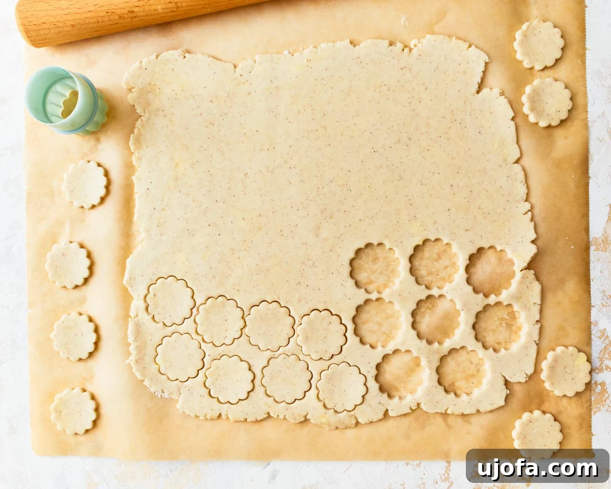 Buttery Golden Gluten-Free Crackers 12 A cookie cutter being used to cut round cracker shapes from the rolled-out gluten-free dough on parchment paper.