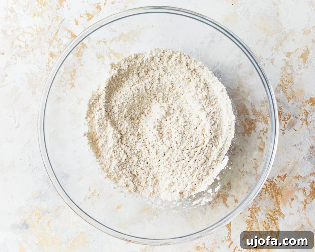 Buttery Golden Gluten-Free Crackers 7 Dry ingredients for gluten-free ritz crackers, including flour, baking powder, sugar, and salt, in a clear glass mixing bowl.