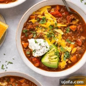 3 bowls of chili with toppings and cornbread on the side