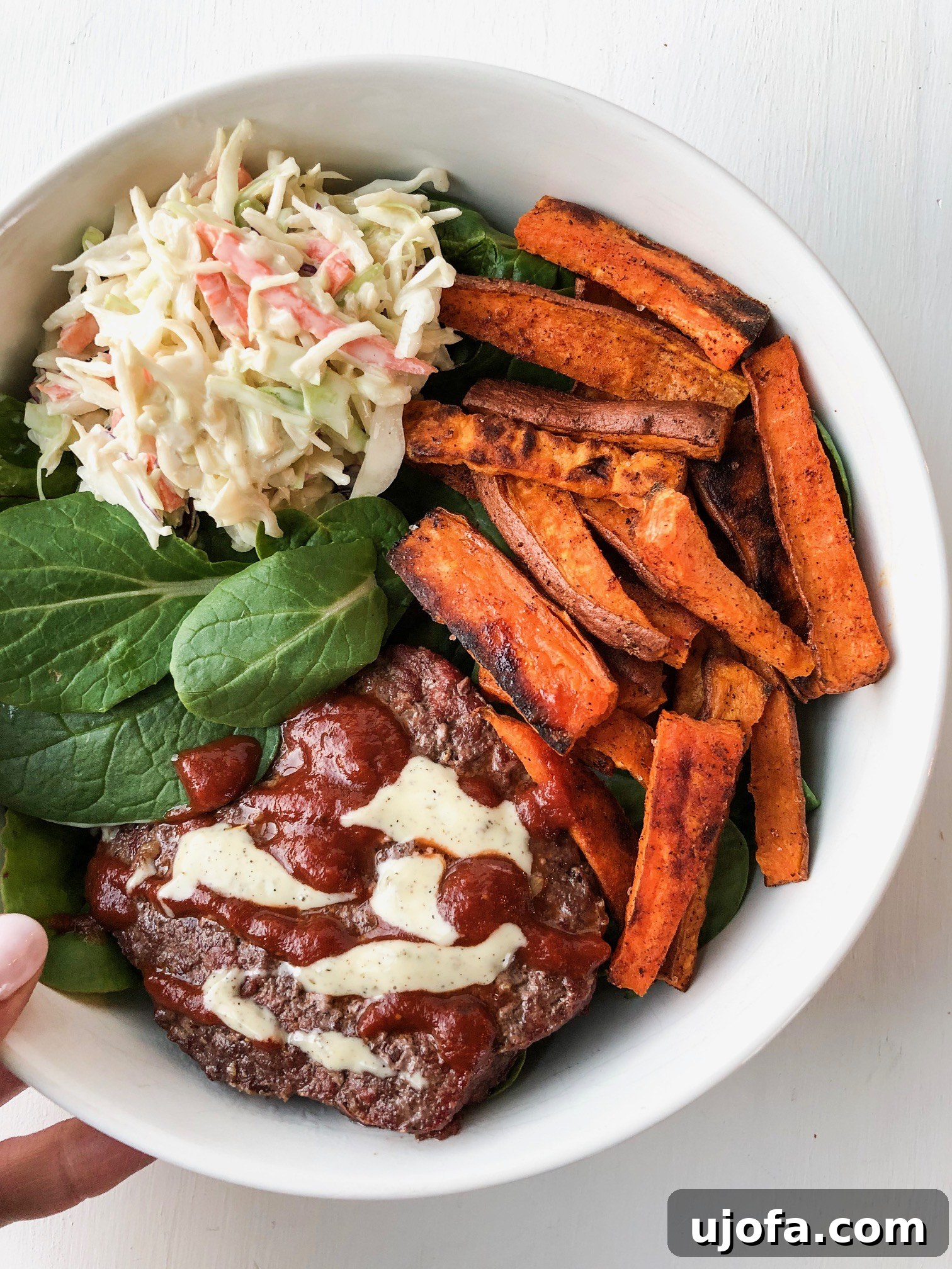Whole30 BBQ Burger Bowl featuring a burger patty, sweet potato fries, and cilantro lime coleslaw.