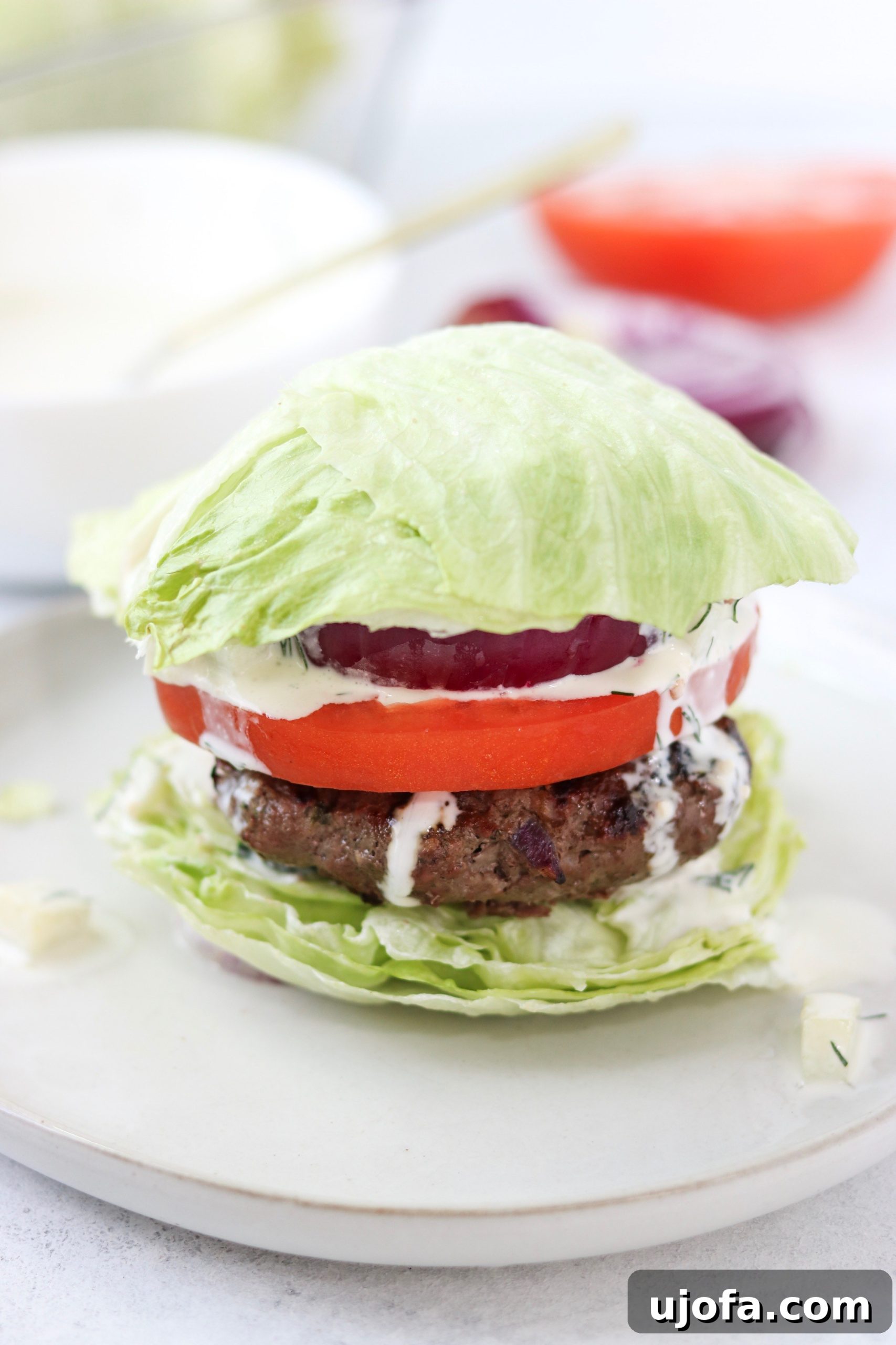 Flavorful Whole30 Lettuce Bun Burger topped with creamy dairy-free tzatziki sauce, served with a side salad.
