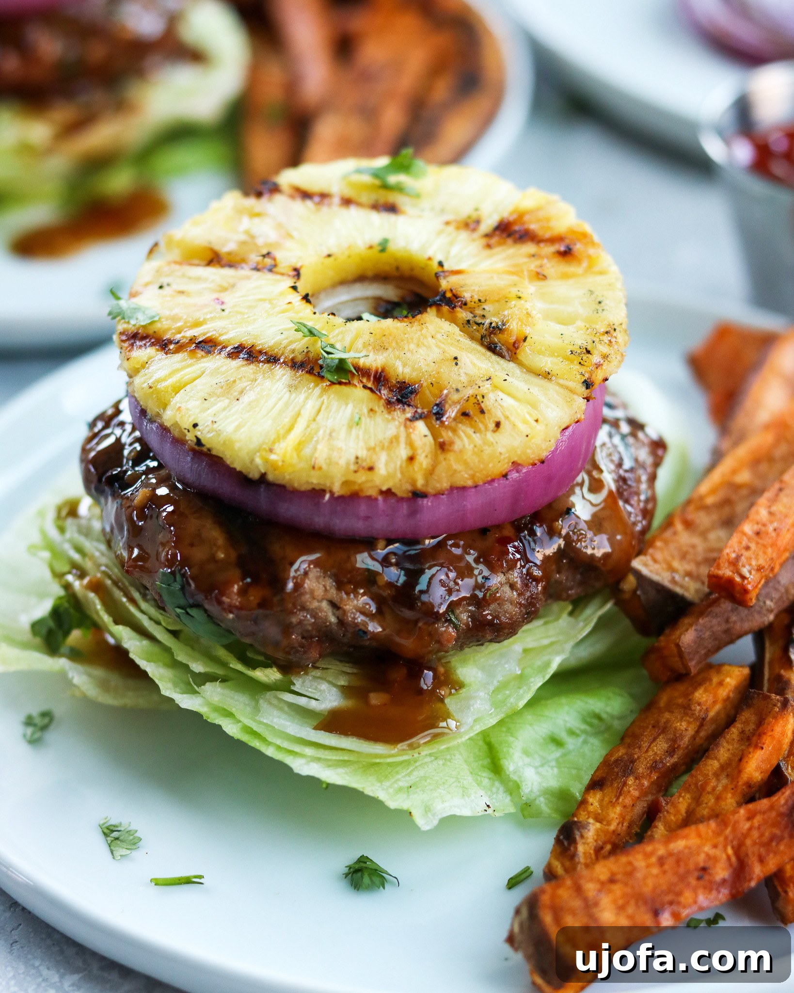 Whole30 Teriyaki Burger topped with a thick slice of grilled pineapple, served on a lettuce bun.