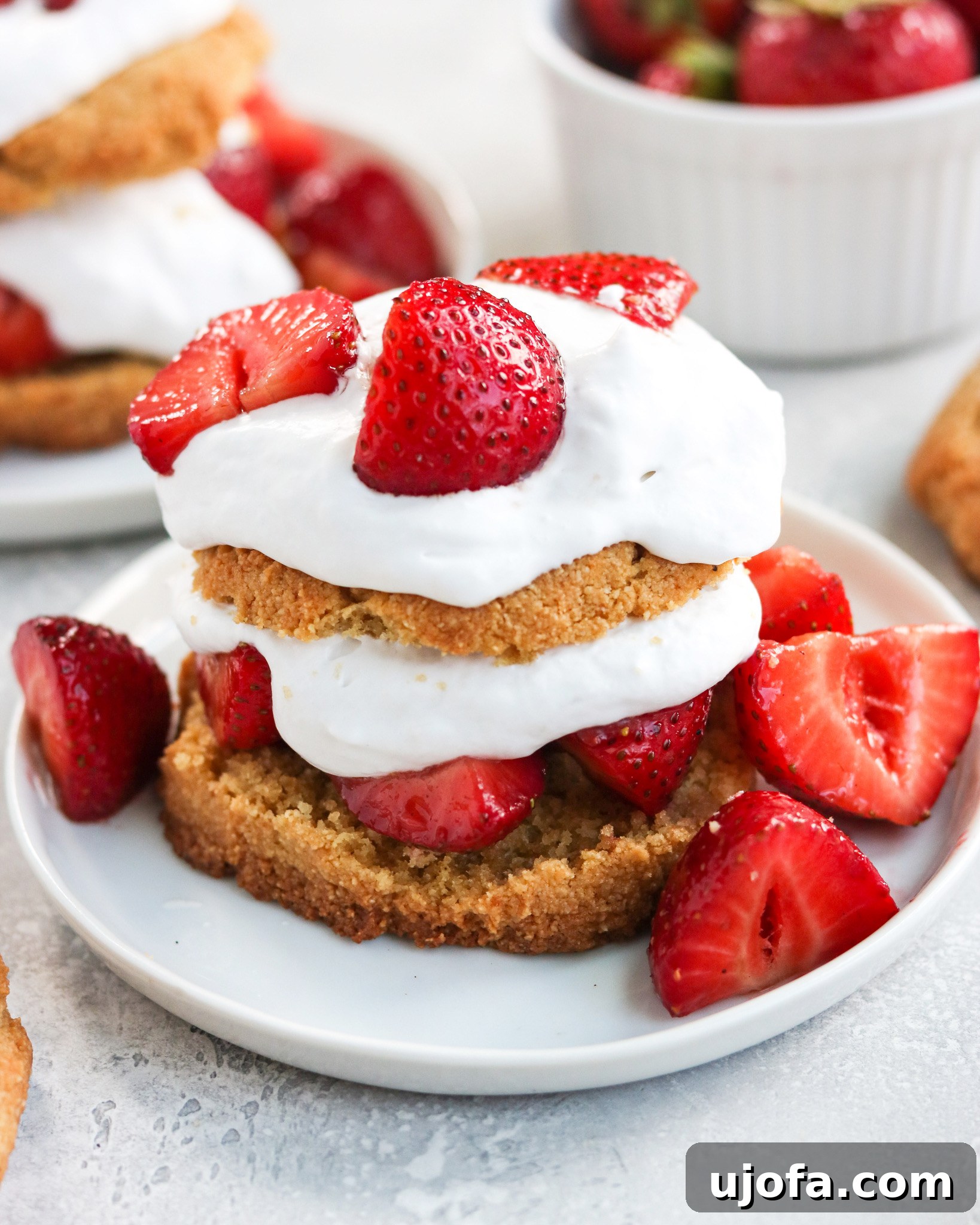 Paleo Strawberry Shortcake with fluffy biscuits, fresh sliced strawberries, and a dollop of coconut cream.