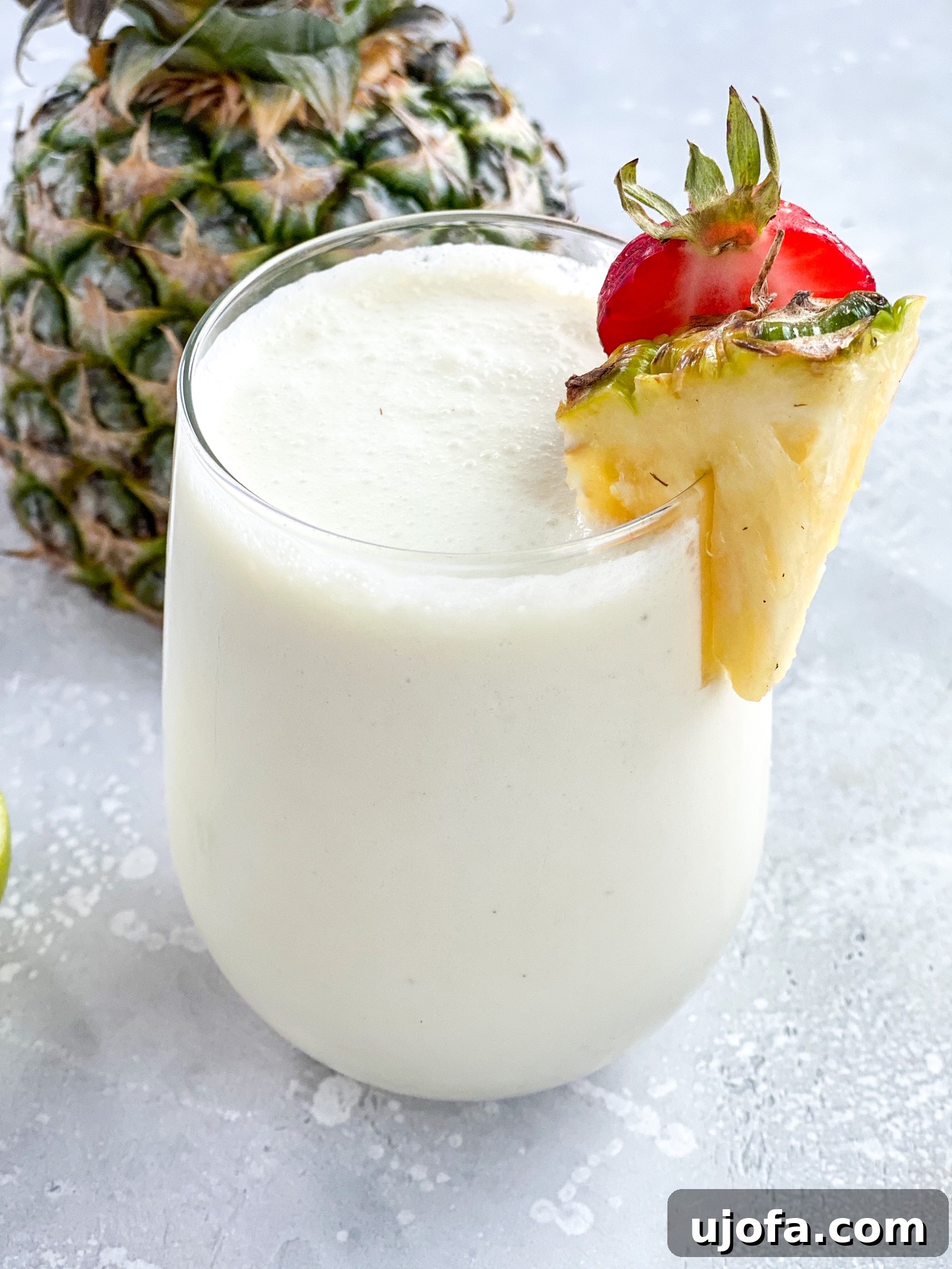 A frosty 3-Ingredient Paleo Pina Colada in a tall glass, garnished with a pineapple wedge.