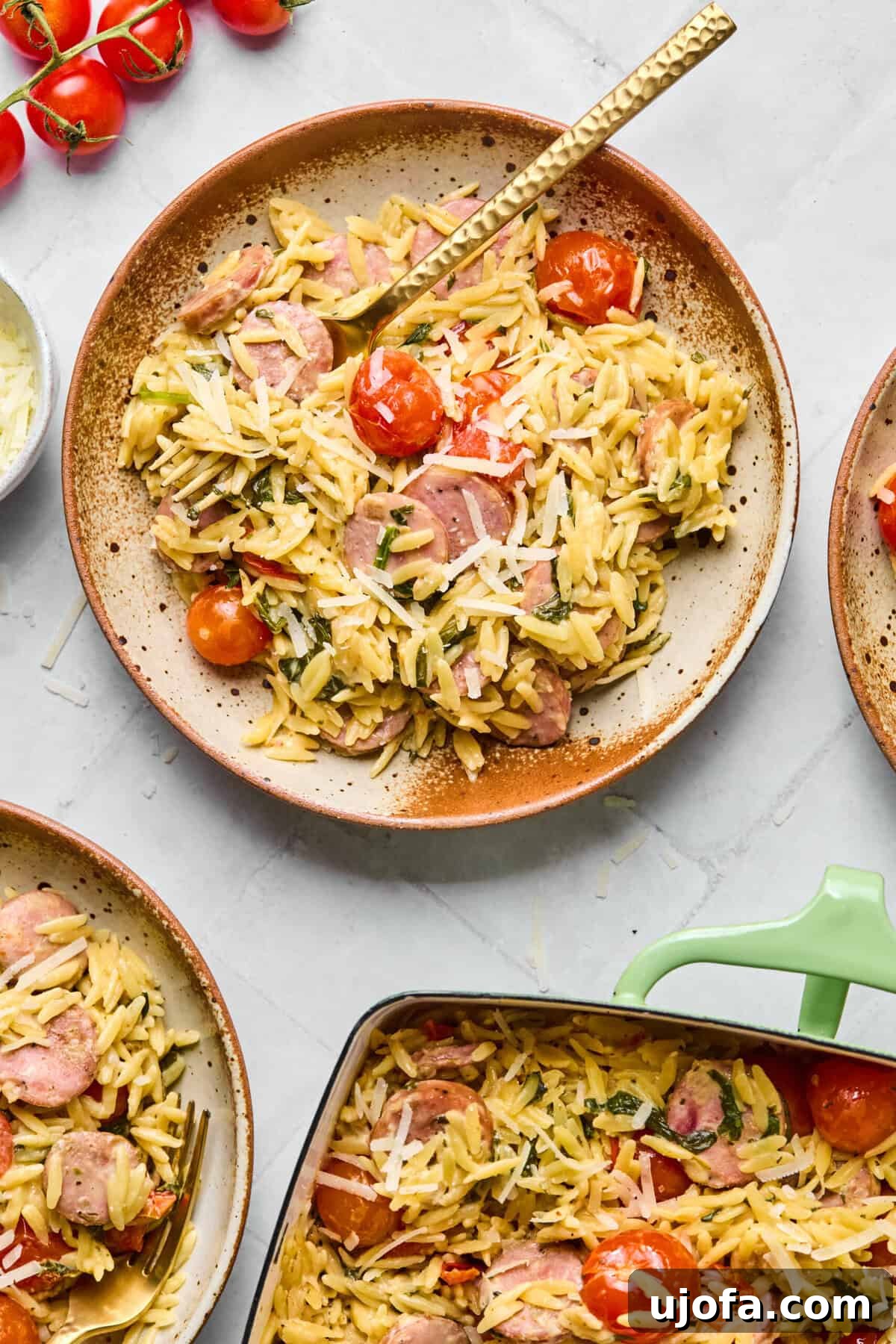 Kremamsı Boursin Orzo Tavuk Sosisli Tek Tencere Keyfi 9 A serving of creamy one pan orzo bake with chicken sausage and spinach on a white plate, with a fork lifting a delicious bite.