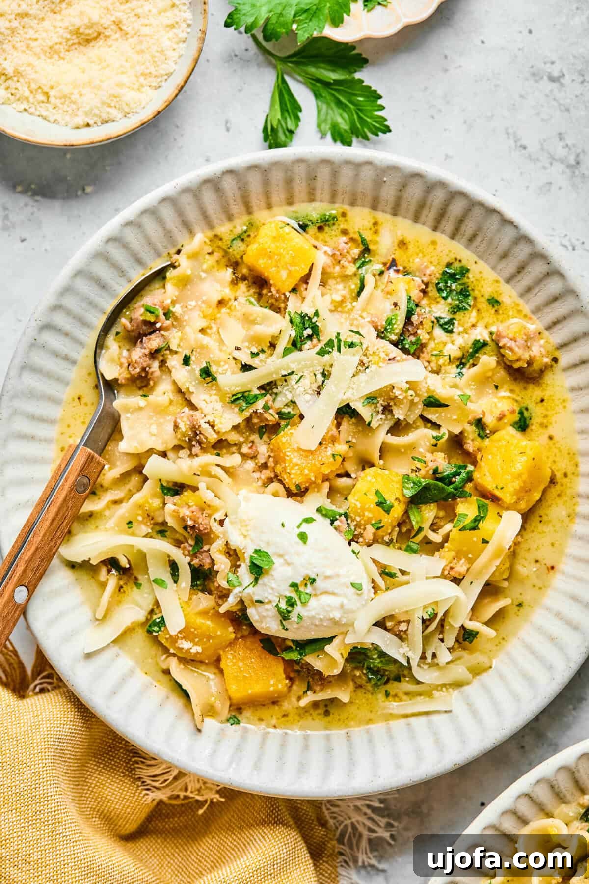 Comforting Butternut Squash Lasagna Soup 2 A beautifully presented bowl of creamy butternut squash lasagna soup, garnished with dollops of ricotta, shredded mozzarella, fresh parsley, and a spoon ready for tasting.