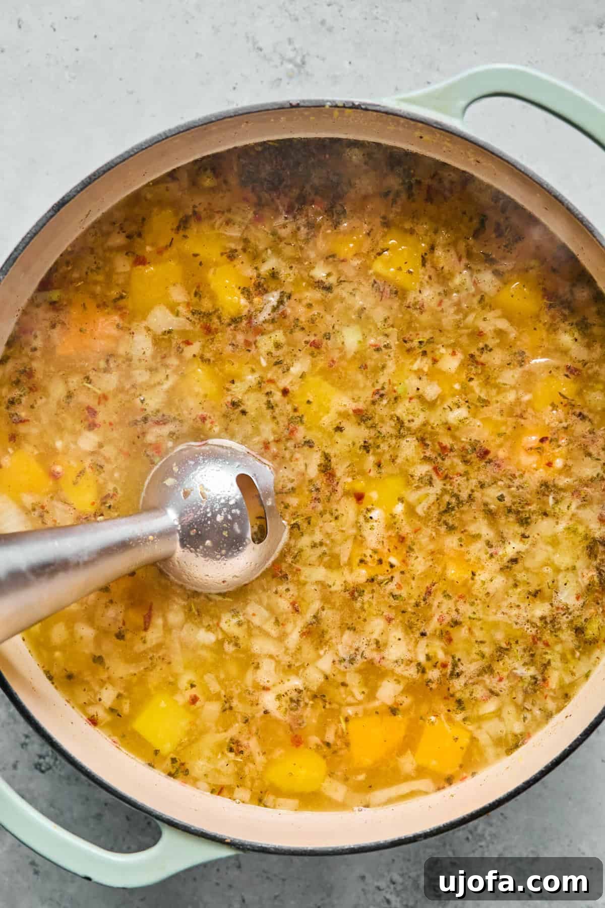 Comforting Butternut Squash Lasagna Soup 7 An immersion blender actively pureeing part of the butternut squash soup base directly in the pot, creating a creamy texture while leaving some squash chunks intact.
