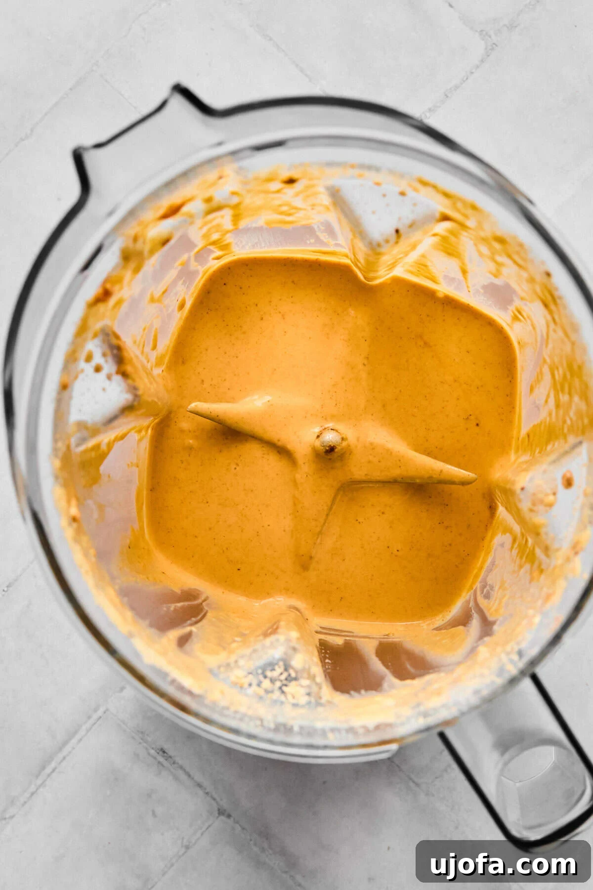 A close-up shot of the pumpkin protein cold foam actively blending in a small blender, showing the mixture transforming into a thick, creamy, and airy consistency with visible froth.