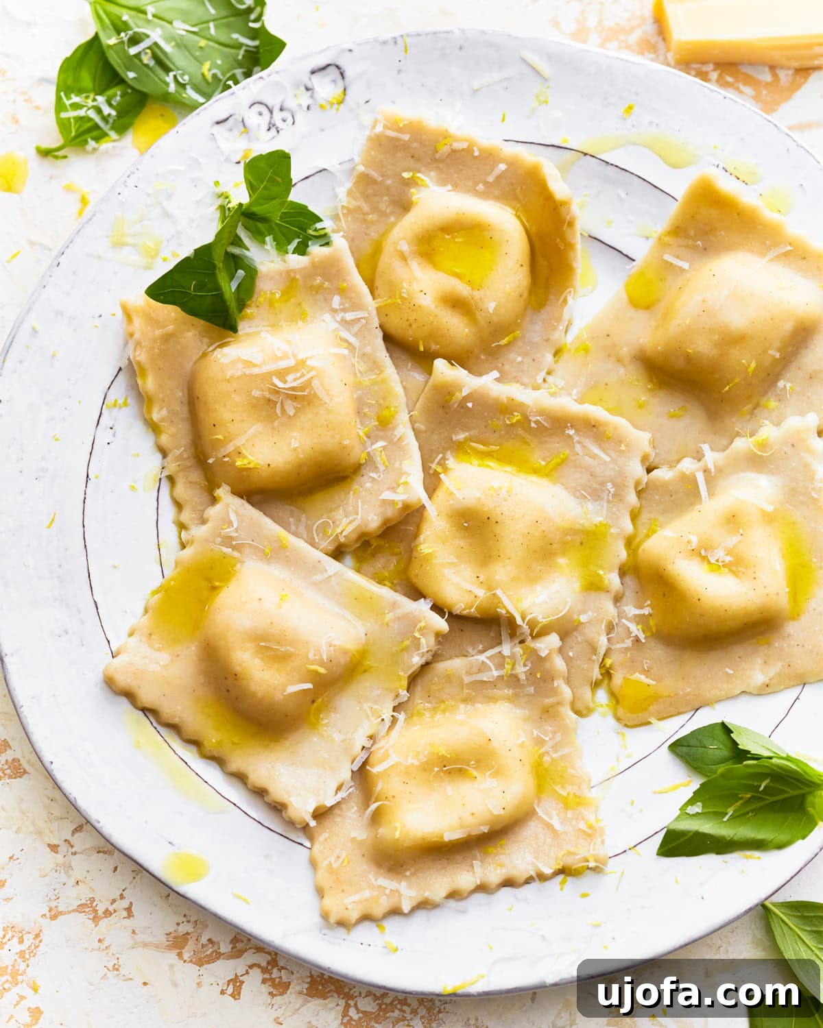 Gluten-free ravioli on a plate with fresh herbs, olive oil, and shredded cheese.